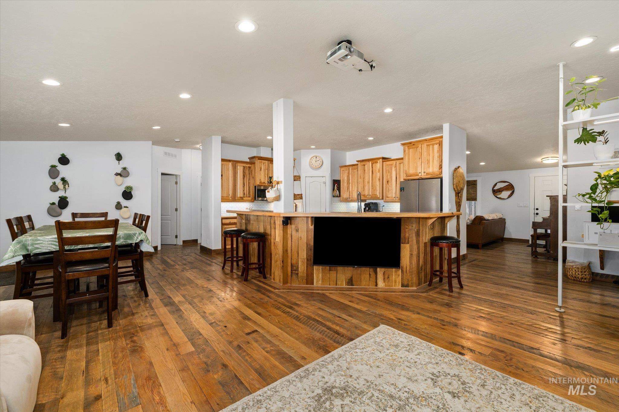 Kitchen with open floor plan, a breakfast bar area, light countertops, dark wood finished floors, and recessed lighting