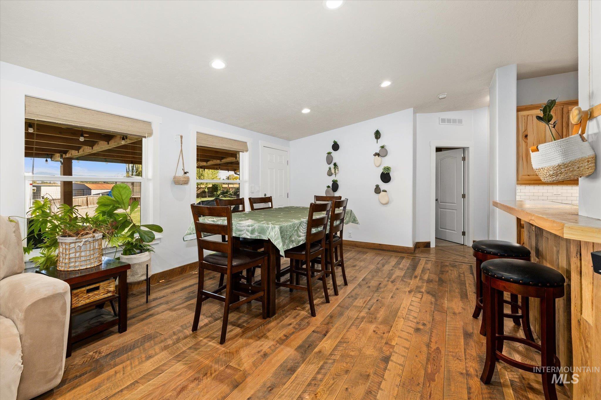 Dining area with dark wood-type flooring, lofted ceiling, and recessed lighting
