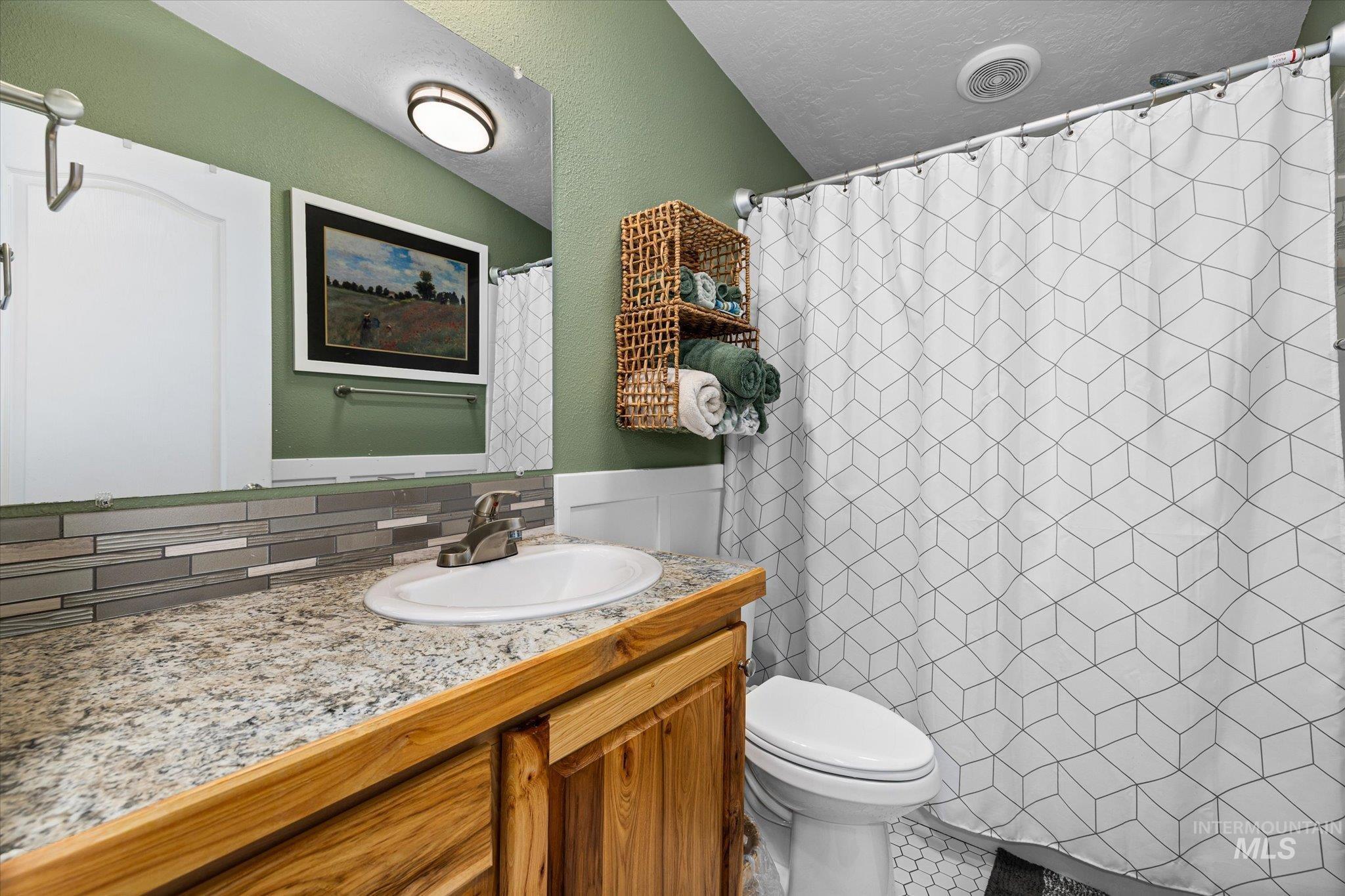 Full bath with vanity, a shower with curtain, a textured ceiling, and decorative backsplash