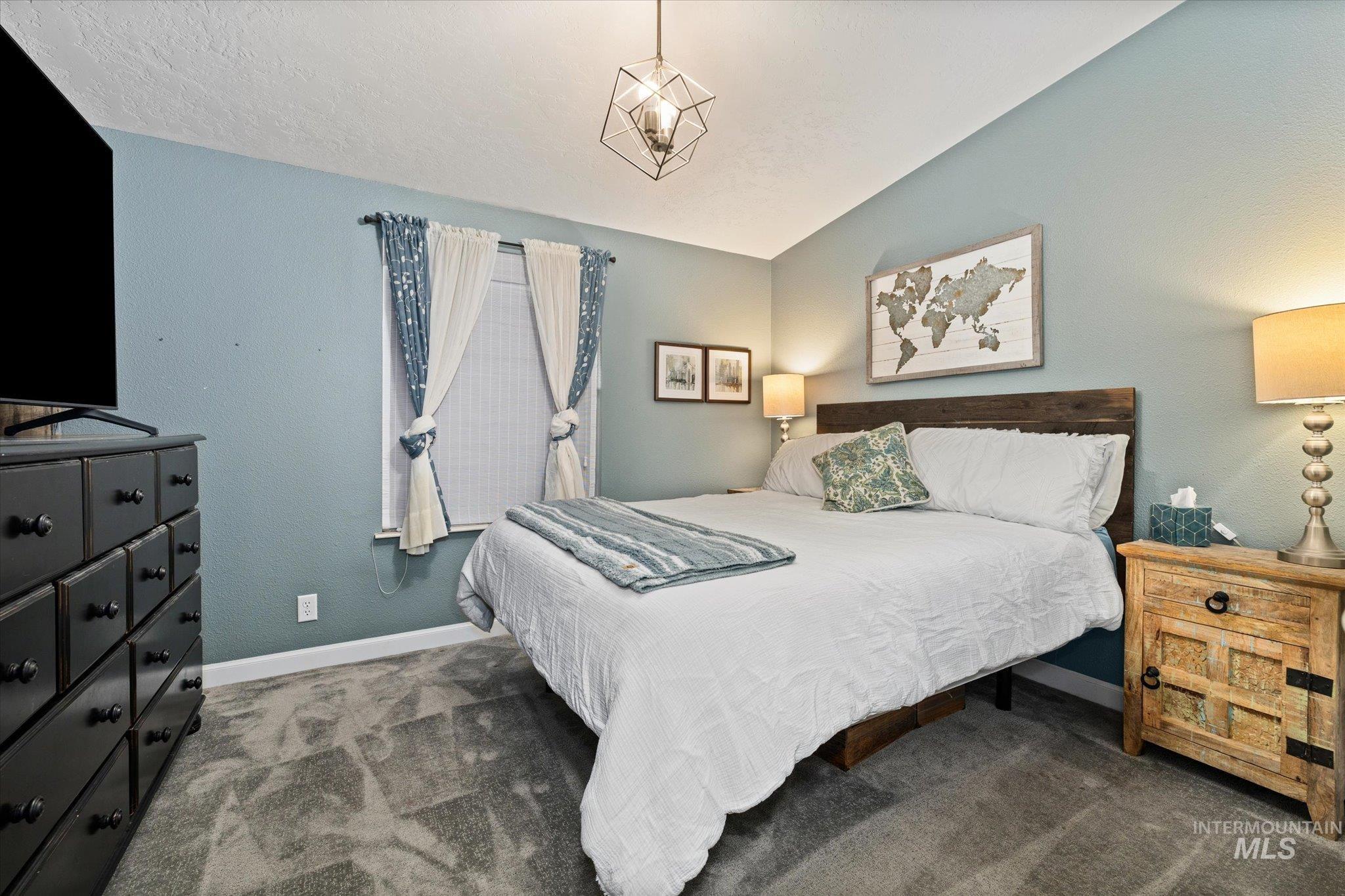 Carpeted bedroom featuring lofted ceiling and a textured wall