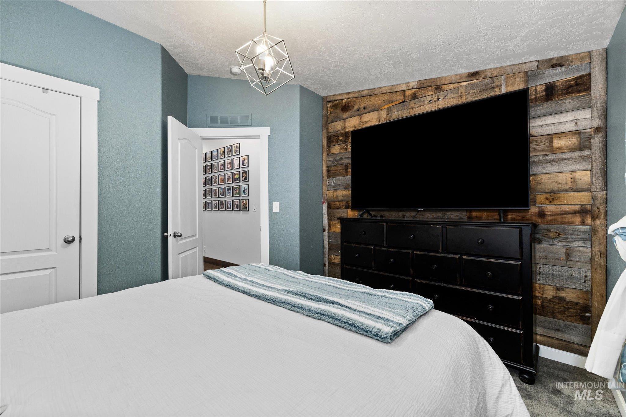 Carpeted bedroom featuring a textured ceiling and a chandelier