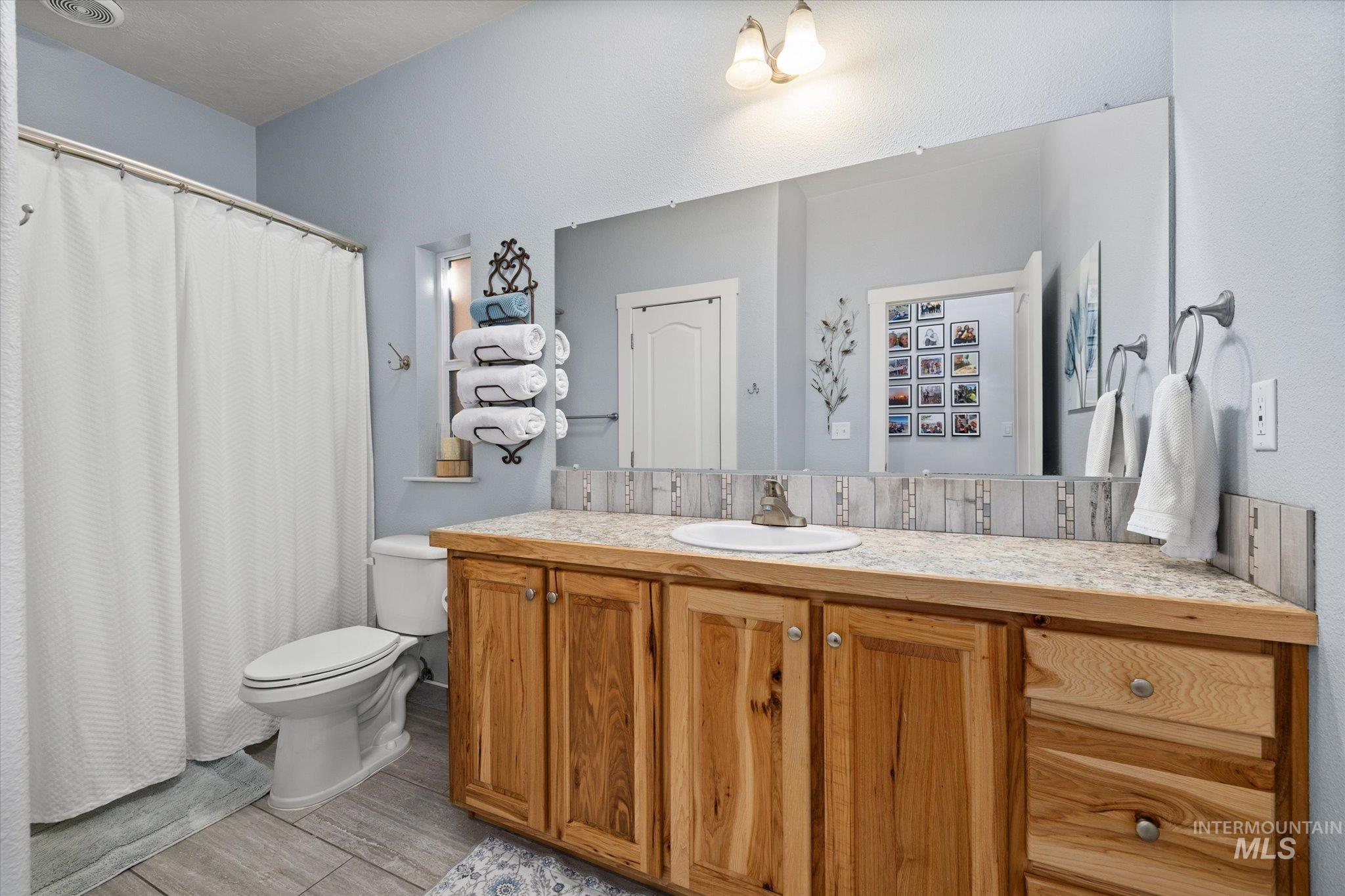 Full bathroom featuring vanity, a shower with curtain, and light wood finished floors