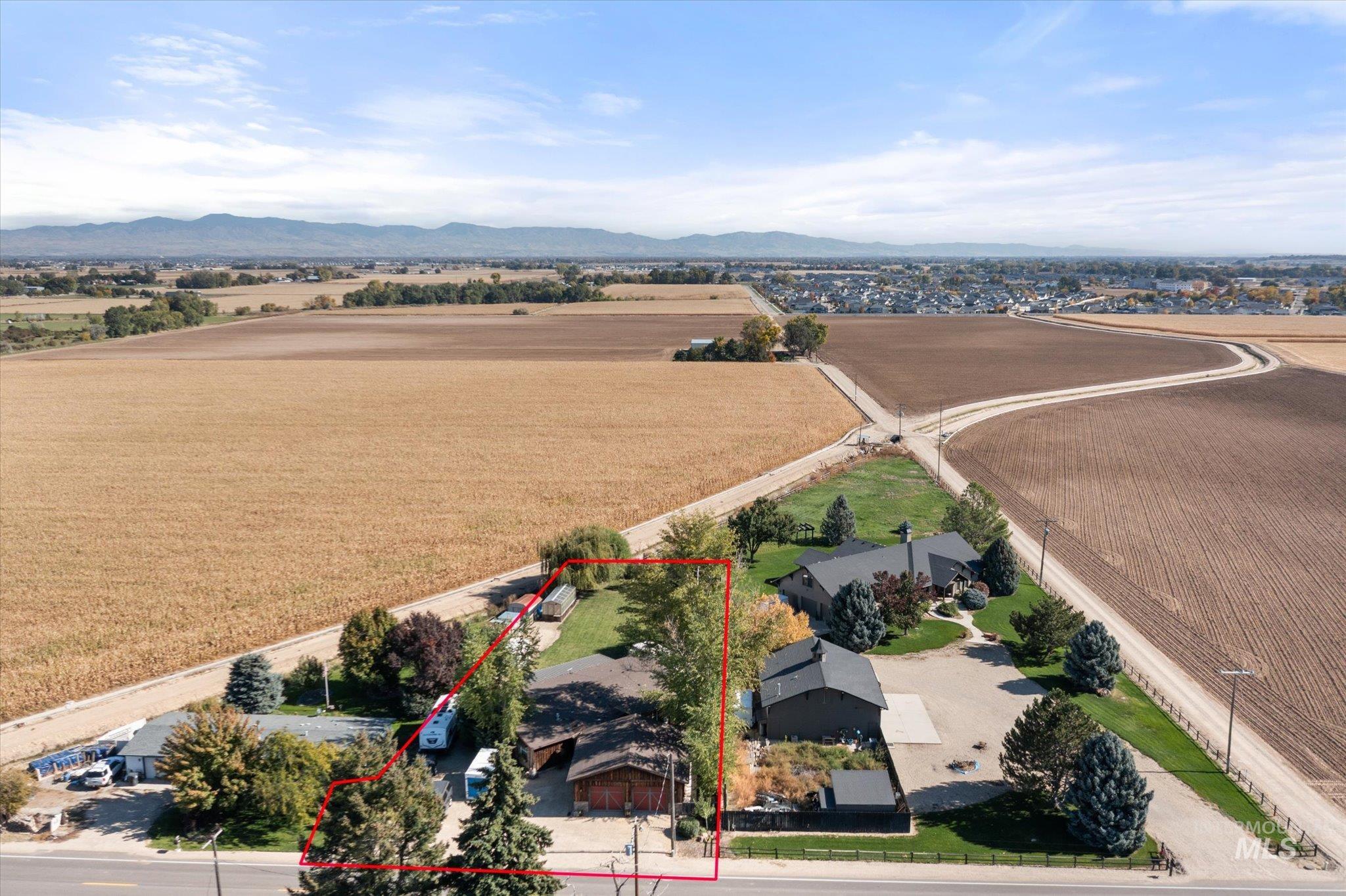 Aerial view of sparsely populated area with a mountain backdrop, property boundaries highlighted, and large plots for crops