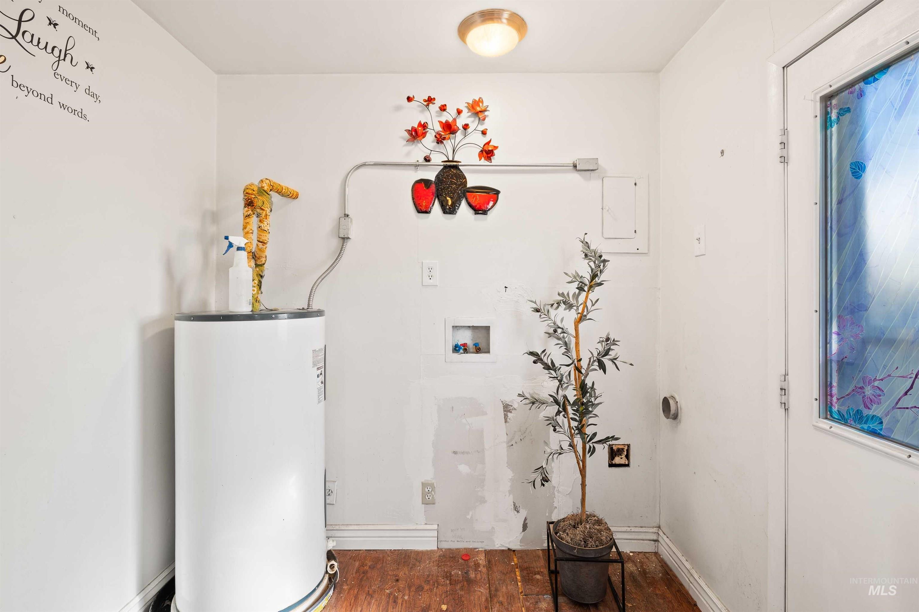 Washroom with wood finished floors, water heater, and hookup for a washing machine