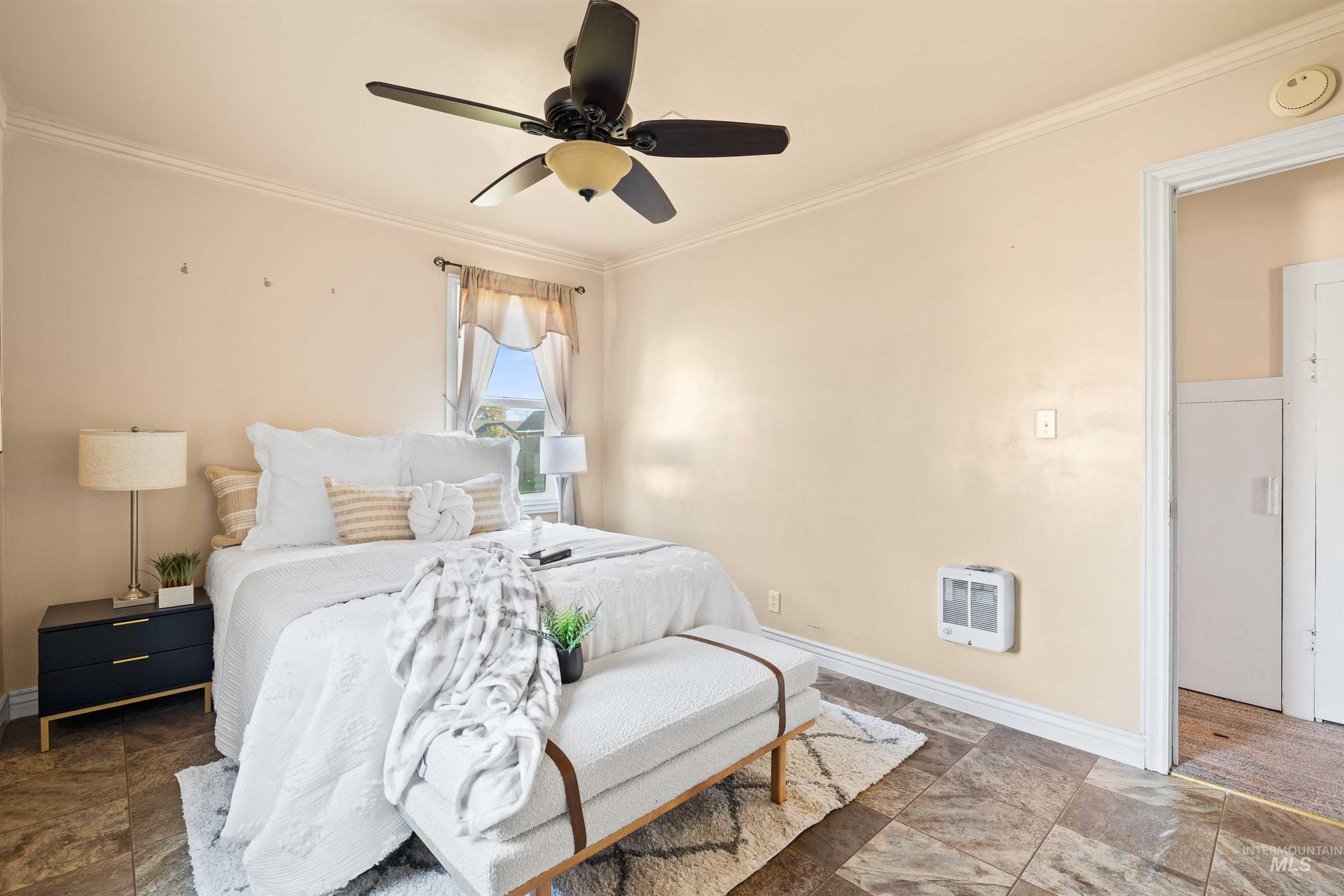 Bedroom with ornamental molding, a ceiling fan, heating unit, and stone finish flooring