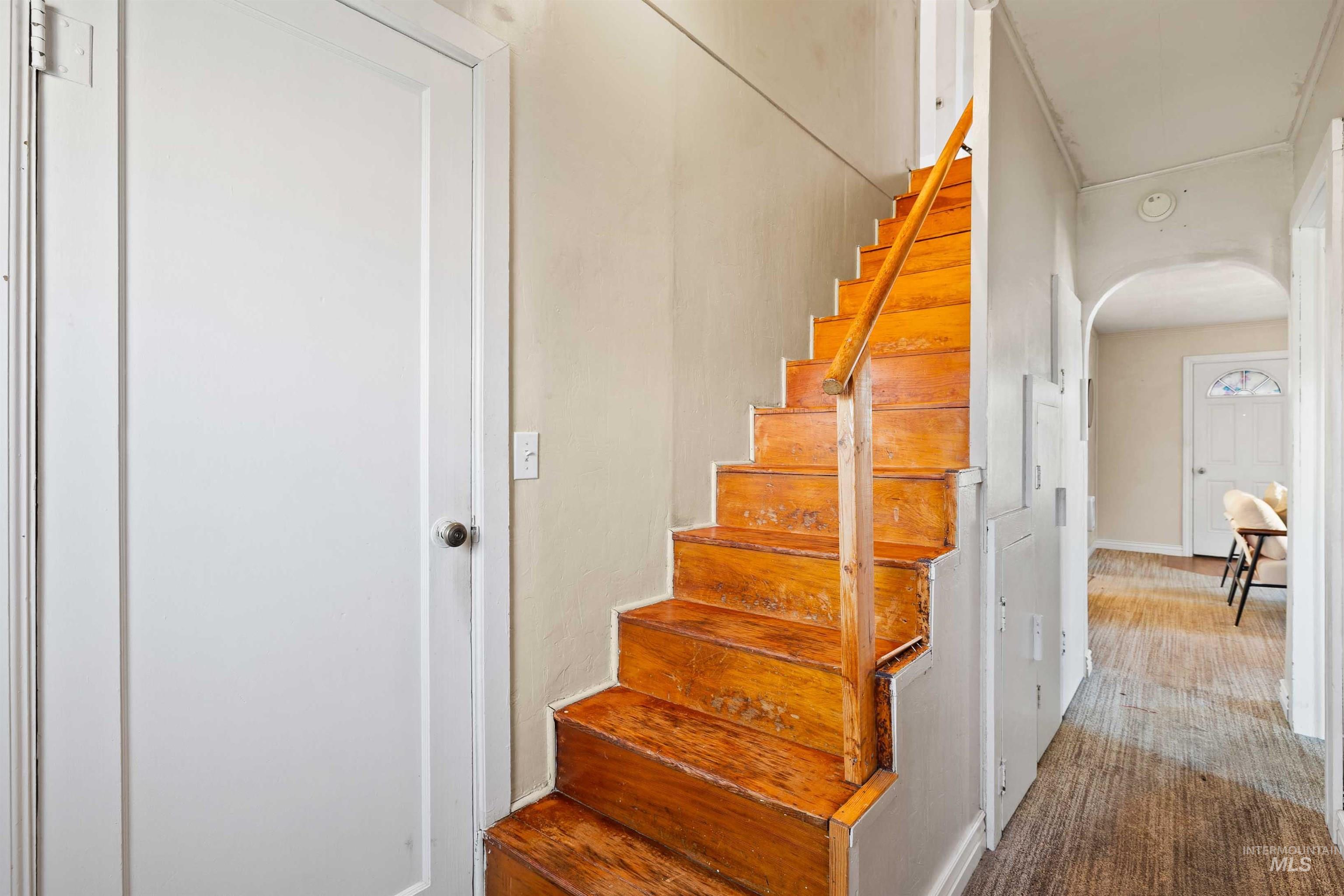 Stairs featuring arched walkways and carpet flooring