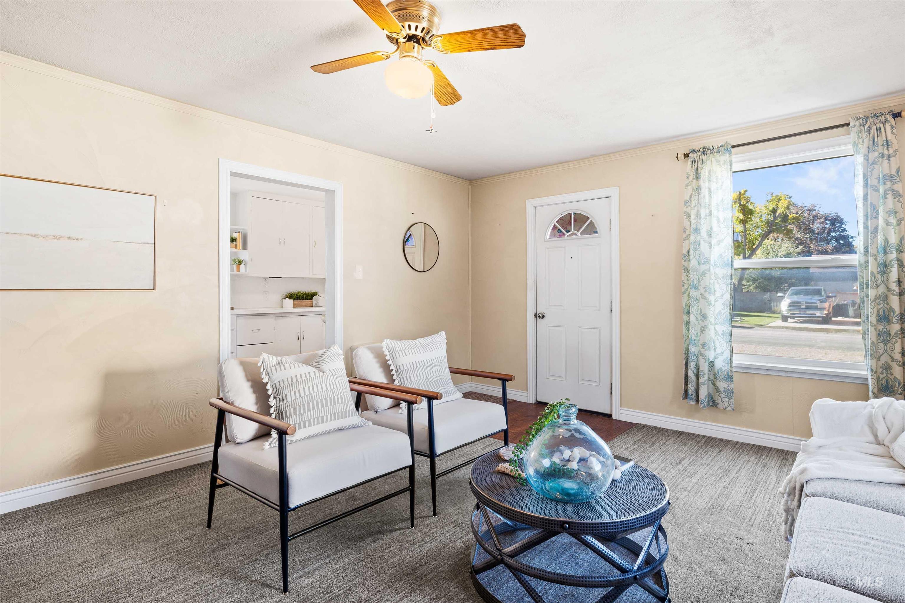 Living area featuring a ceiling fan, carpet, and ornamental molding