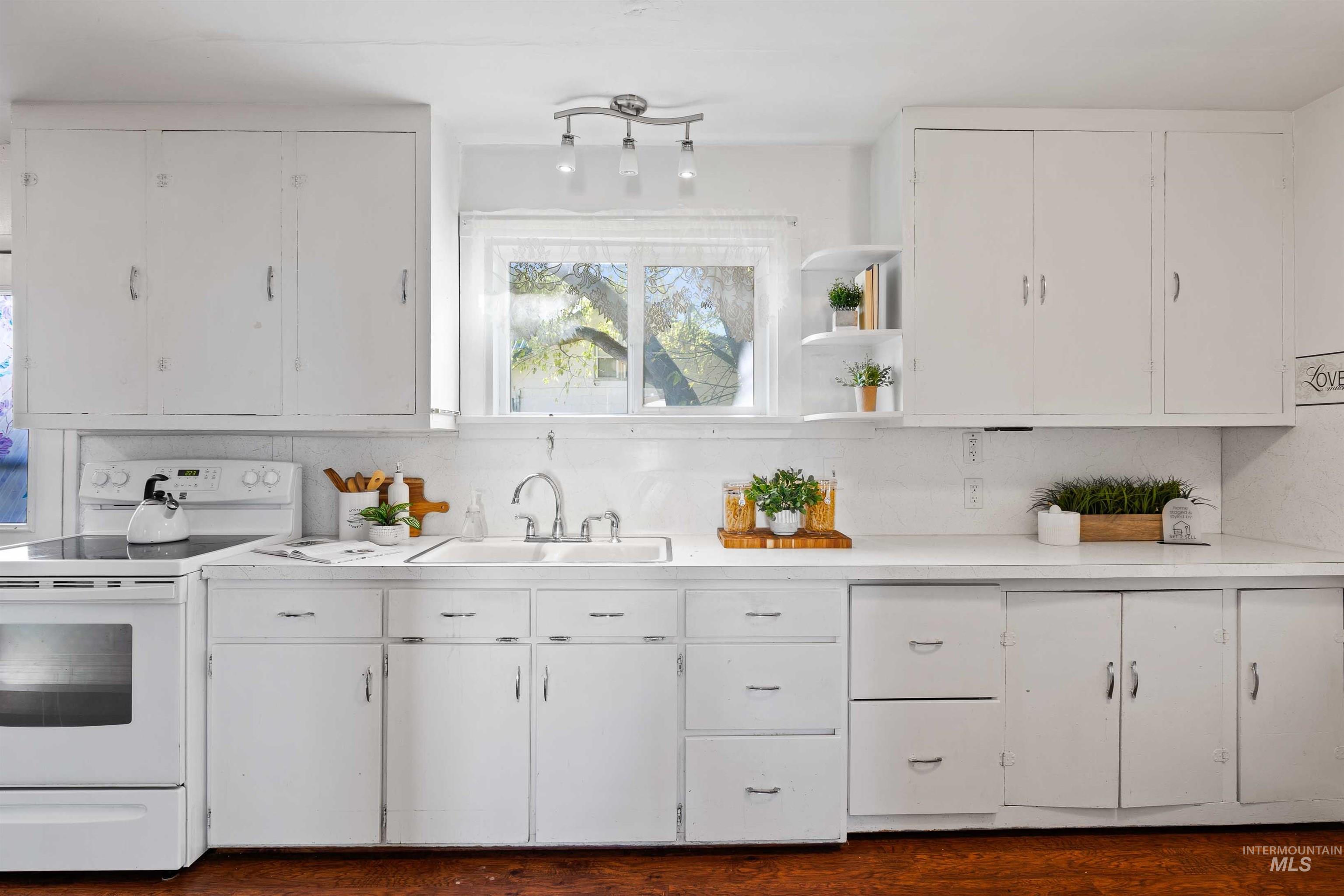 Kitchen featuring white range with electric stovetop, white cabinetry, and light countertops