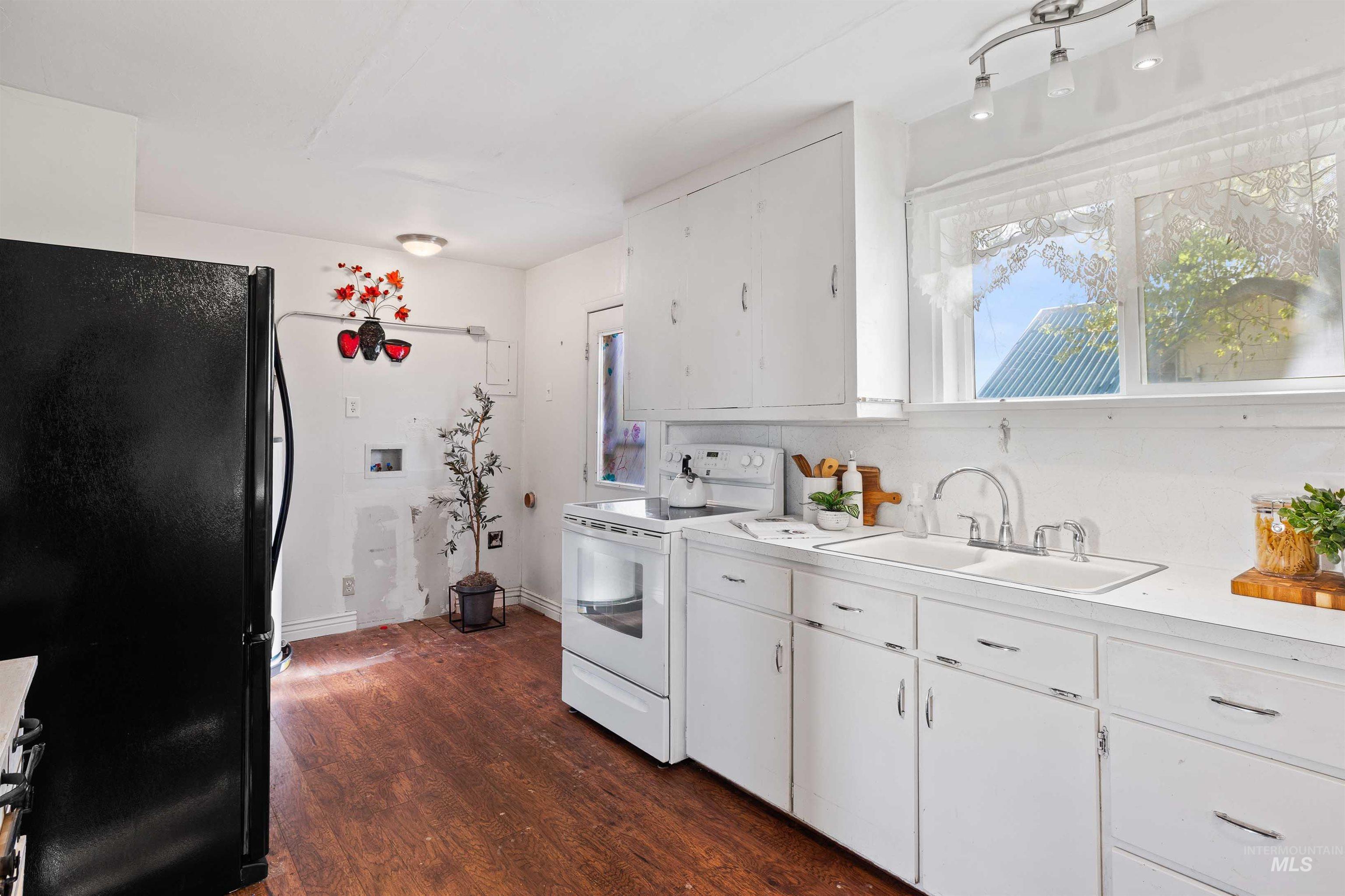 Kitchen with white cabinets, freestanding refrigerator, dark wood-type flooring, white electric stove, and light countertops