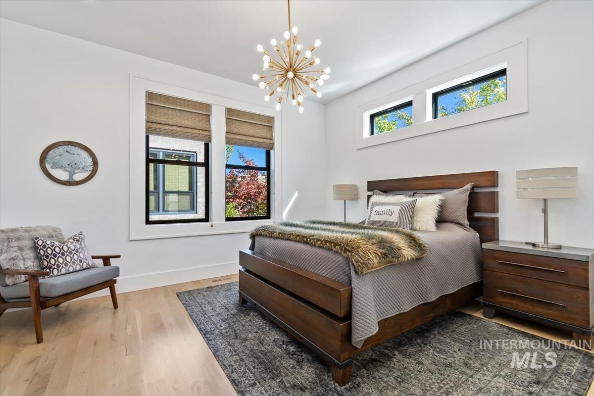 Bedroom featuring multiple windows, wood finished floors, and a chandelier
