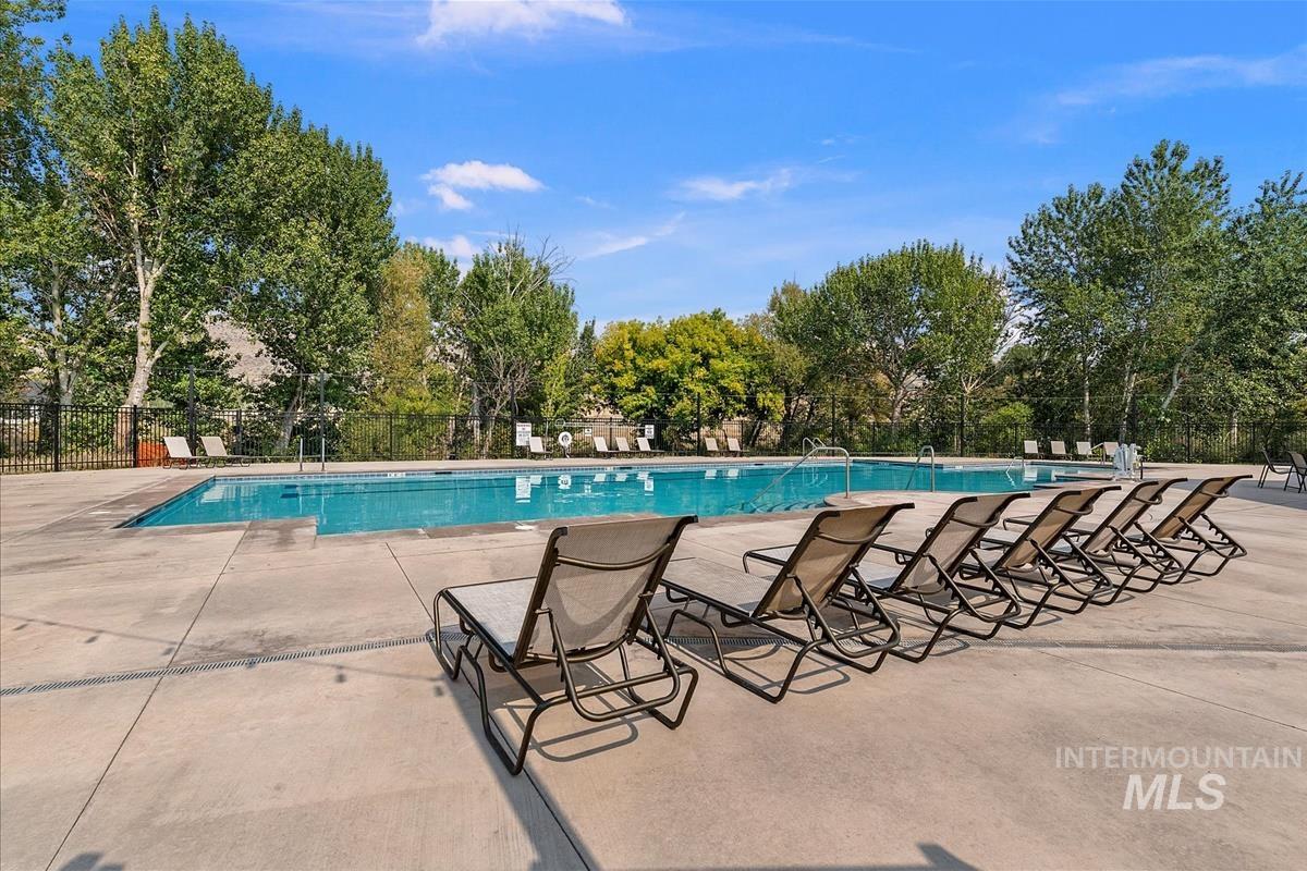Community pool featuring a patio and view of wooded area