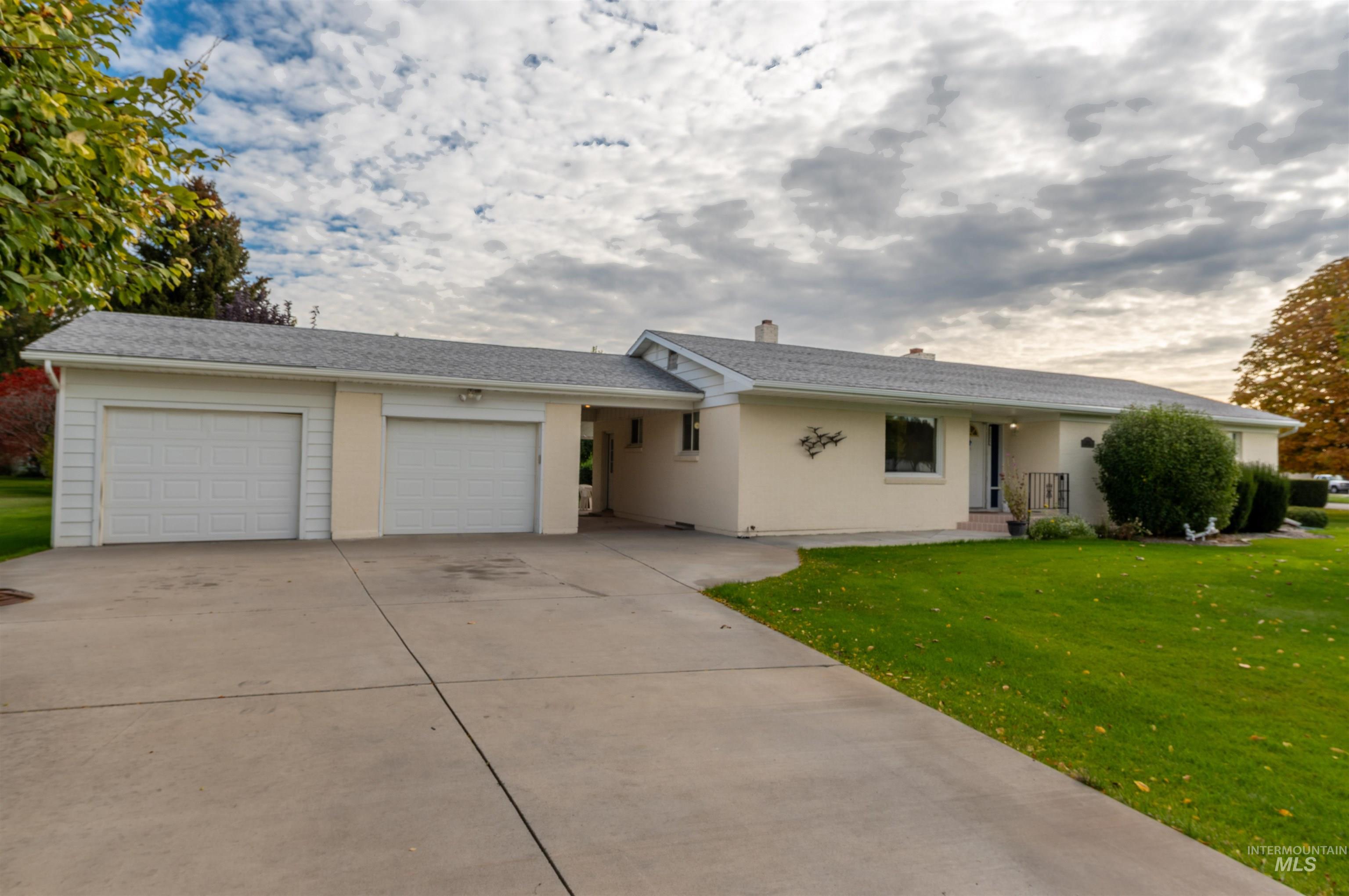 Ranch-style home with a front lawn, concrete driveway, an attached garage, and a chimney