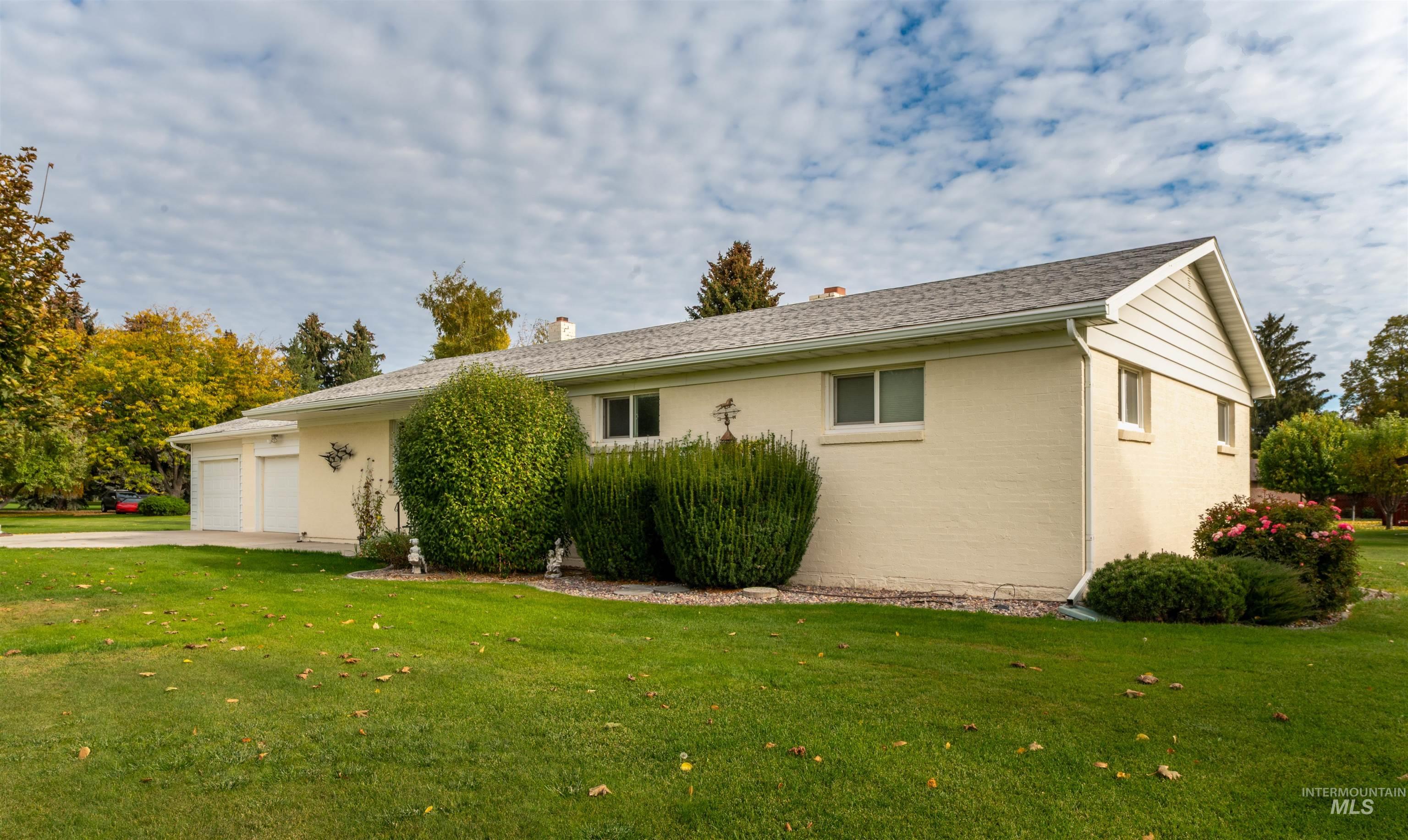 View of home's exterior with a lawn, a chimney, an attached garage, driveway, and brick siding