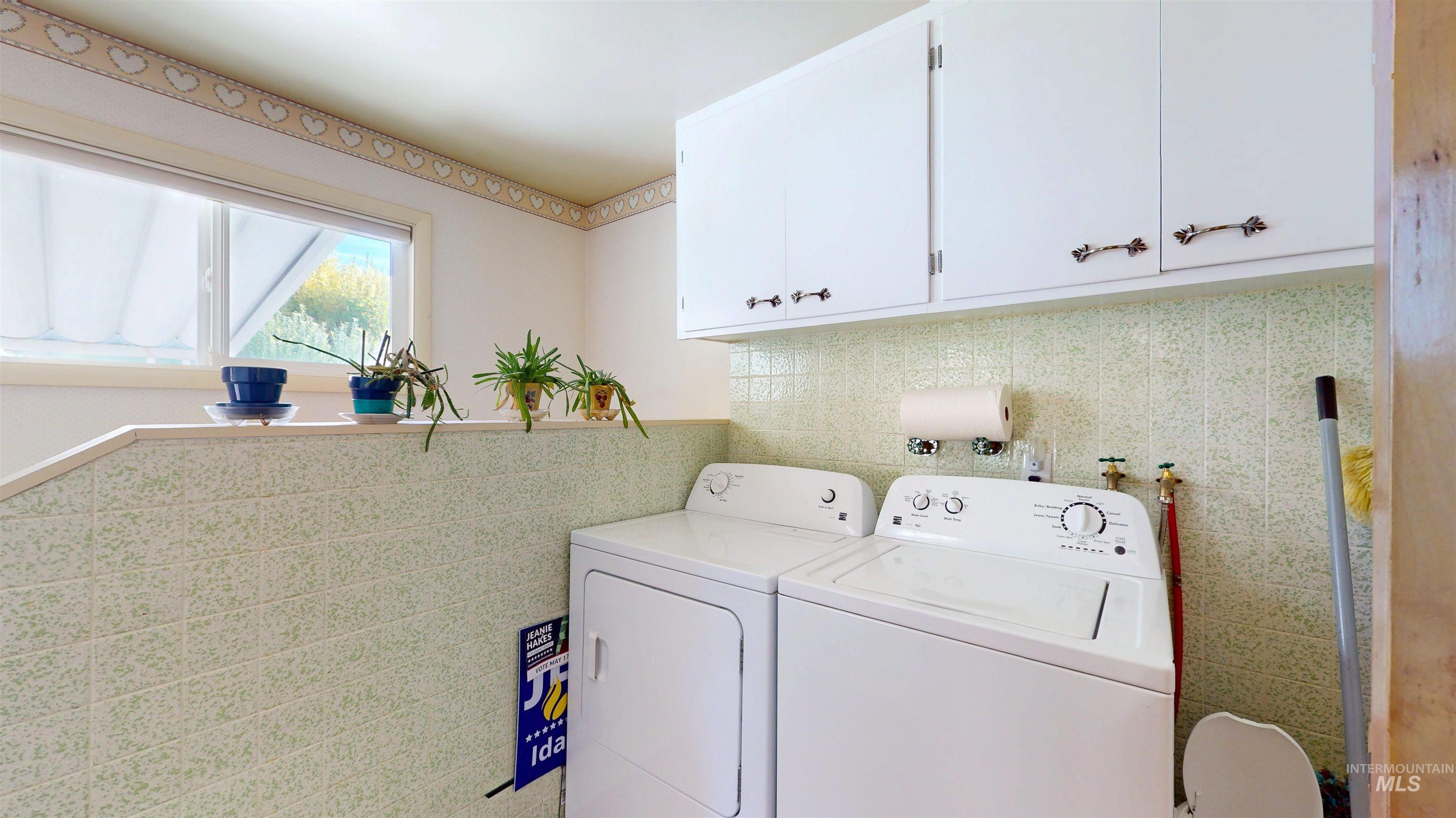Laundry area featuring tile walls and washing machine and dryer