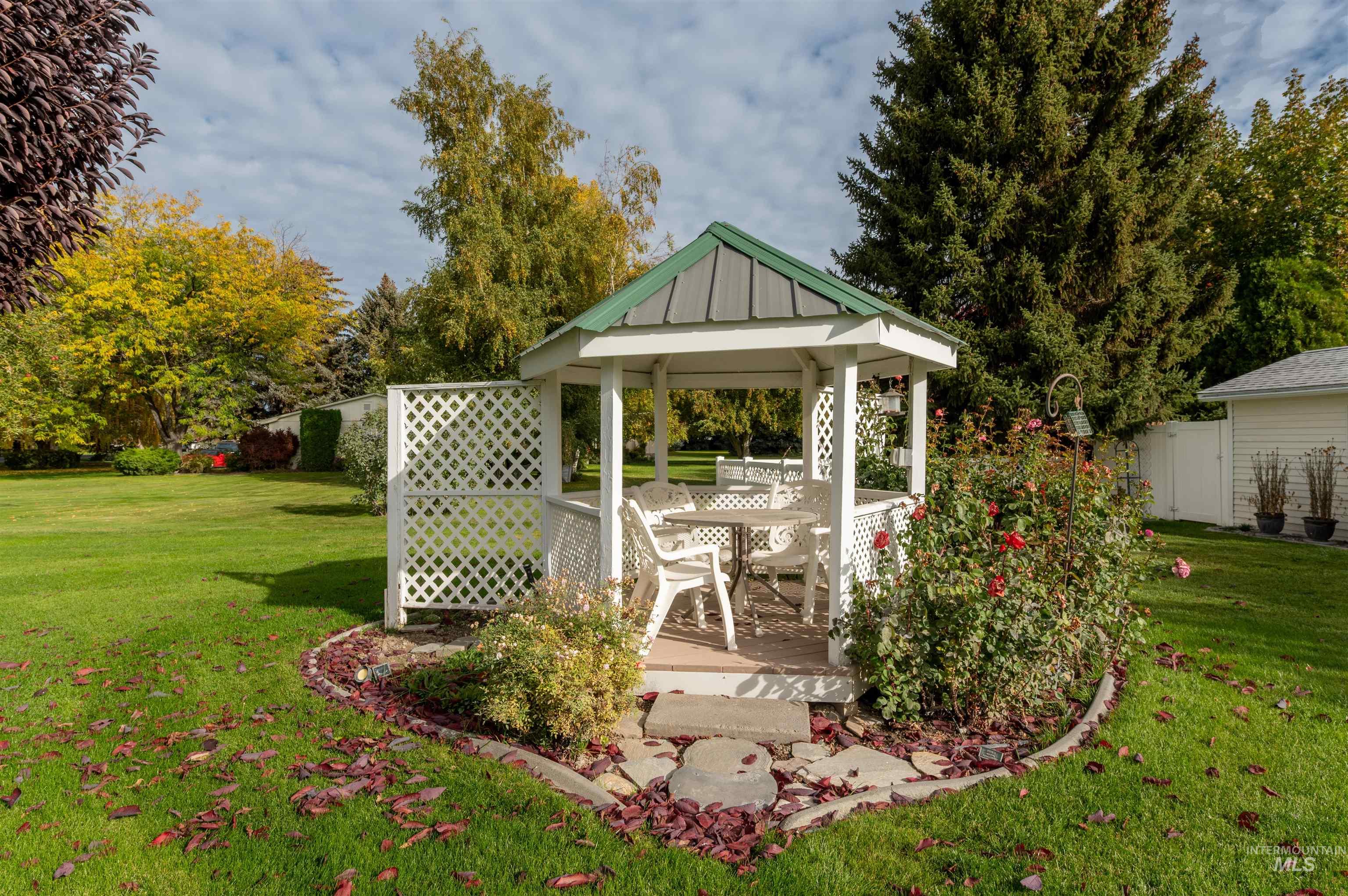 View of grassy yard featuring a gazebo, a deck, and view of wooded area