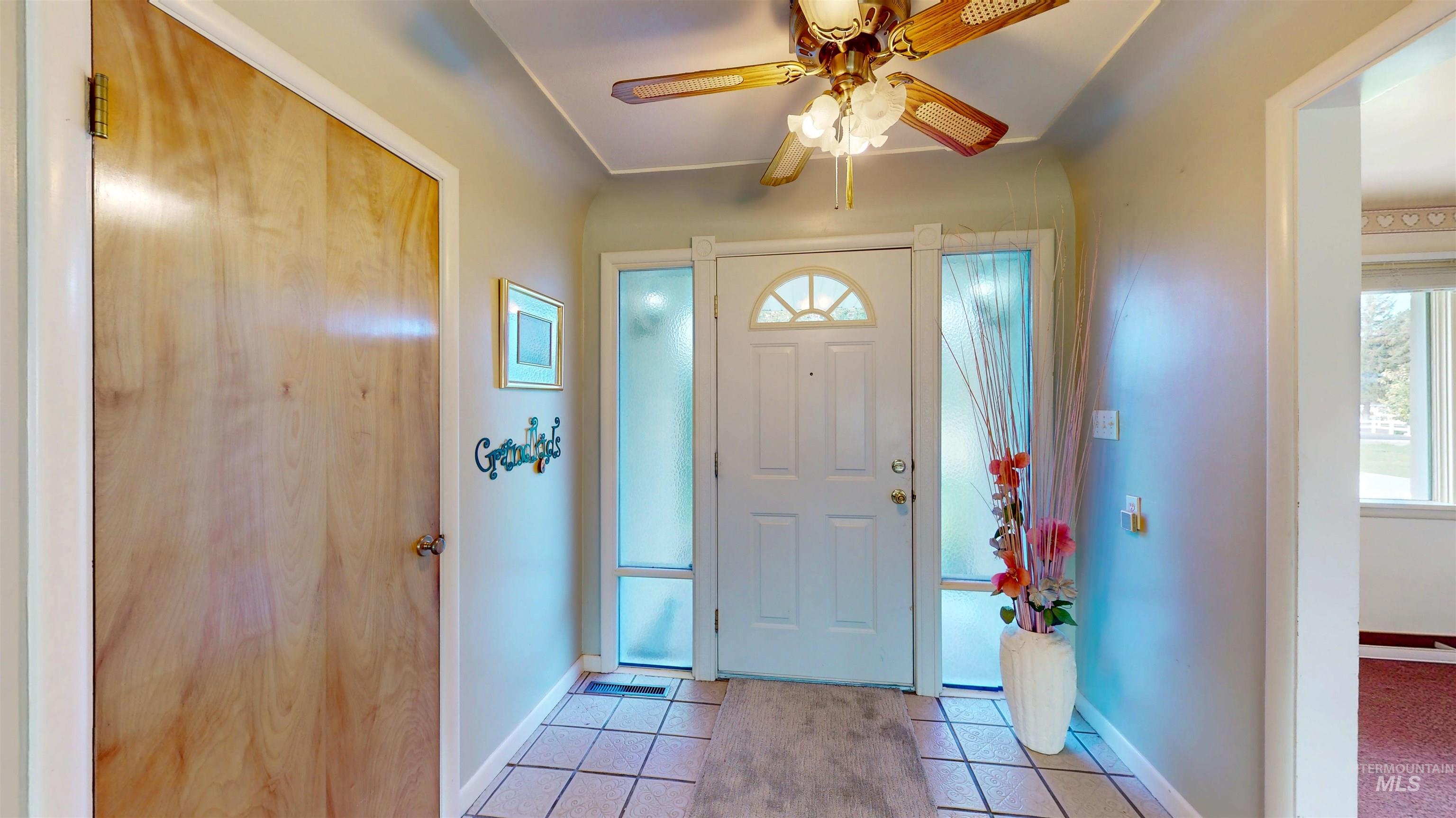 Foyer with tile patterned floors and ceiling fan