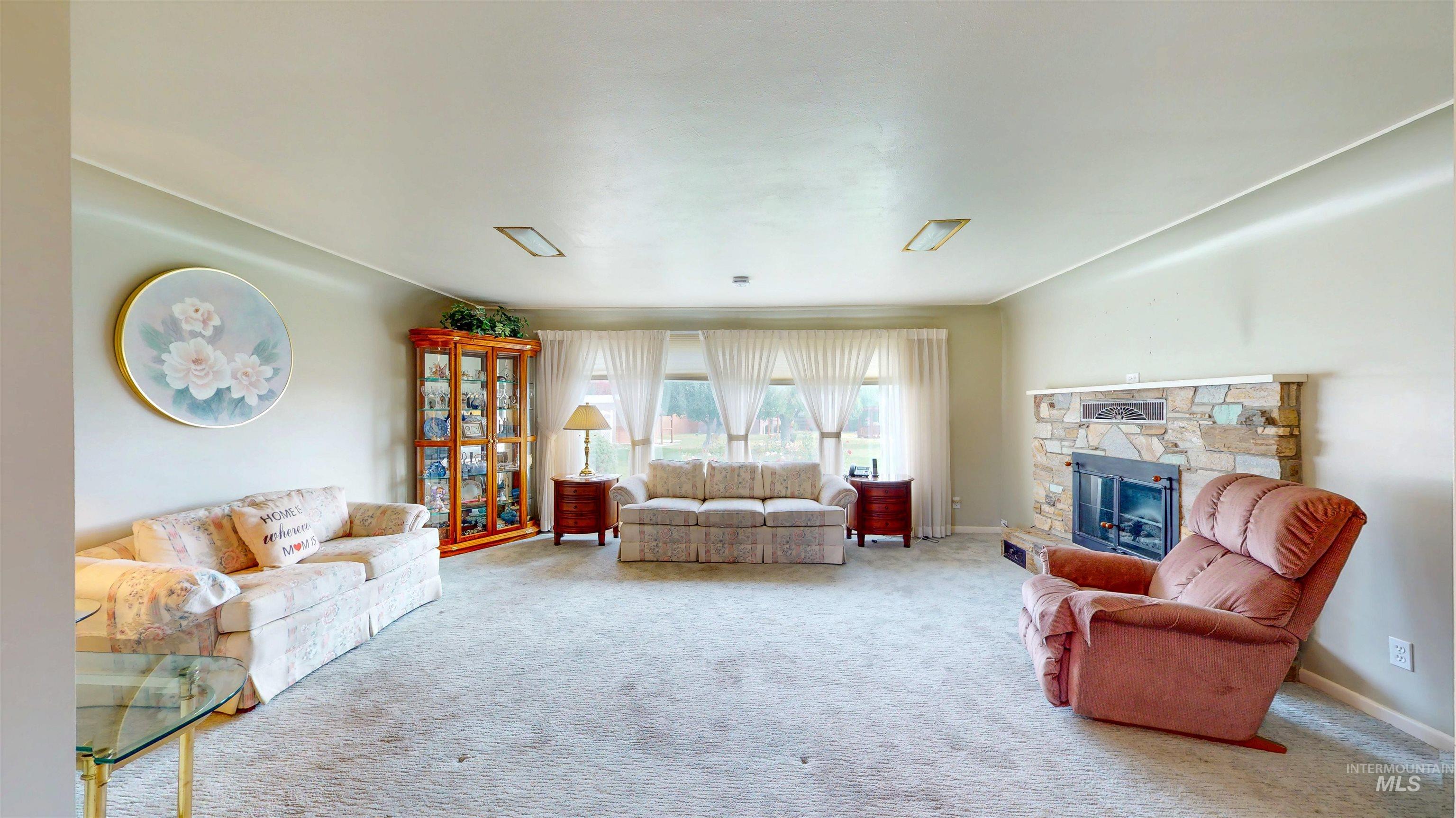 Living area featuring a stone fireplace and carpet flooring