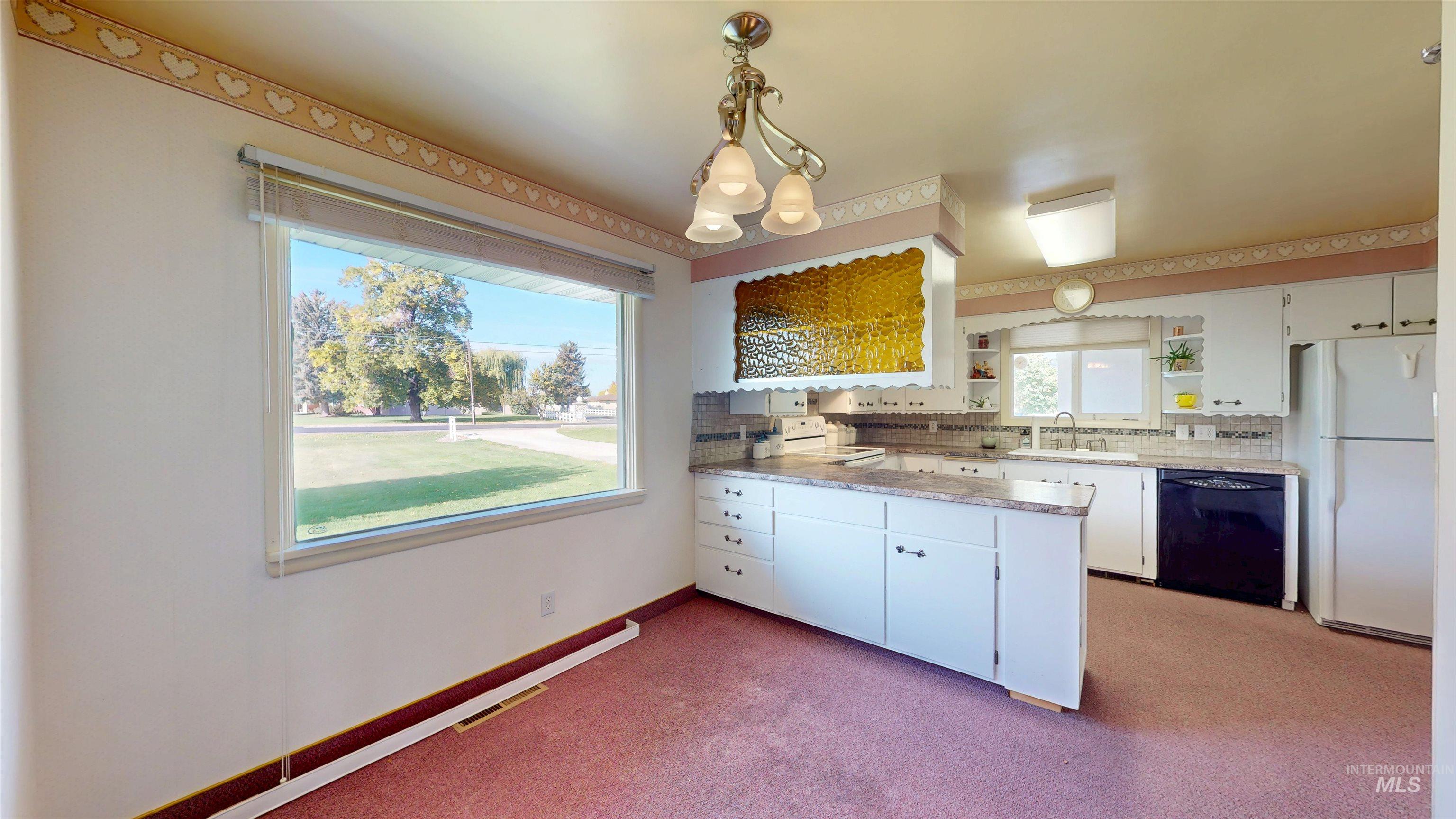 Kitchen with white appliances, white cabinetry, pendant lighting, light colored carpet, and light countertops