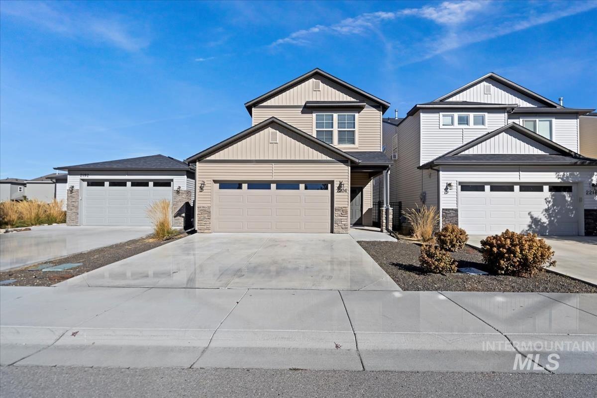 View of front of property with stone siding, concrete driveway, a garage, and board and batten siding