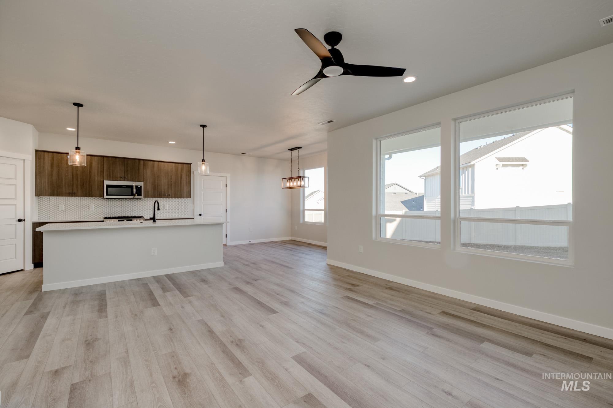 Unfurnished living room featuring a ceiling fan, light wood-type flooring, and recessed lighting
