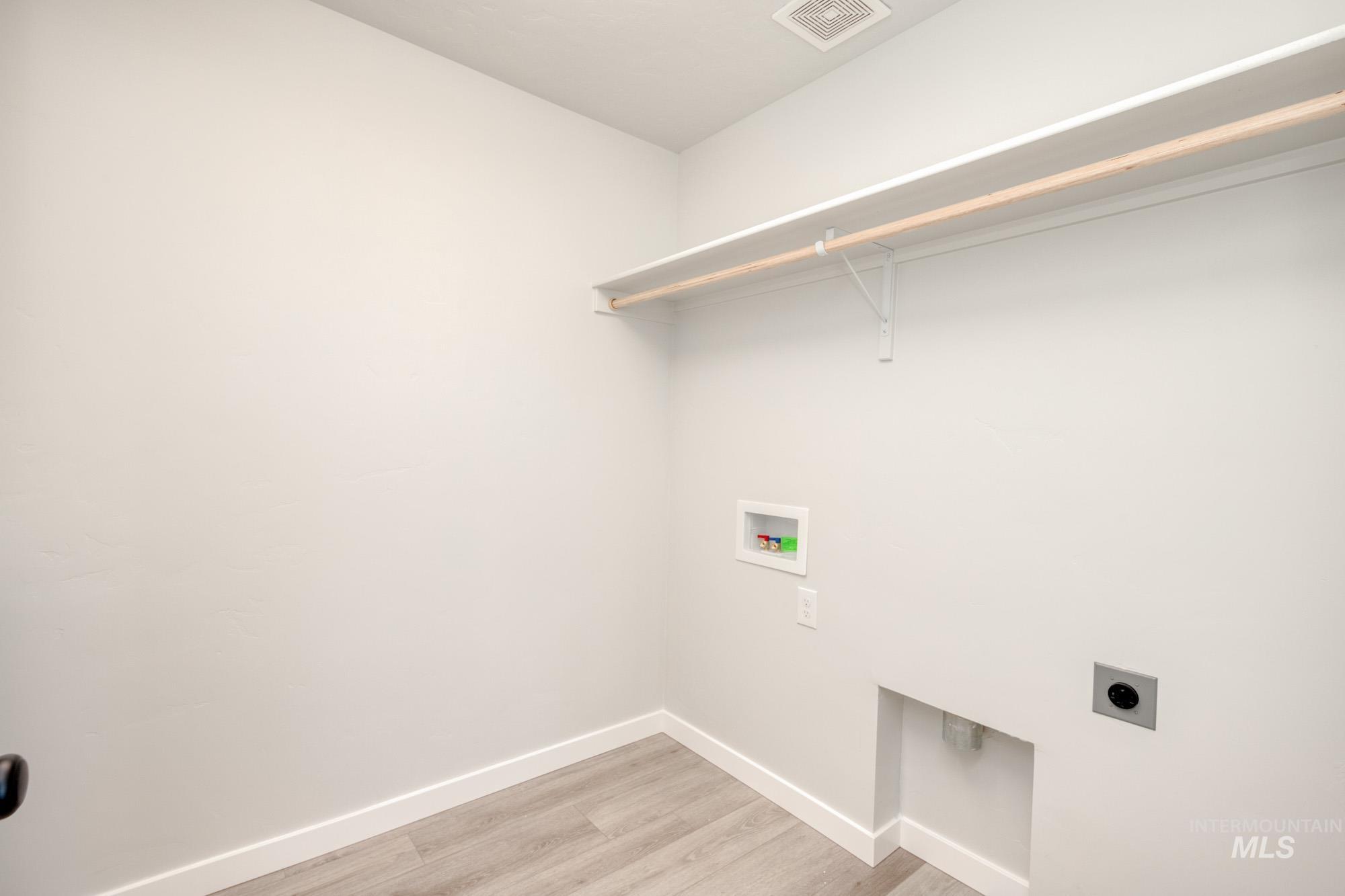 Laundry room with light wood-type flooring, hookup for an electric dryer, and washer hookup