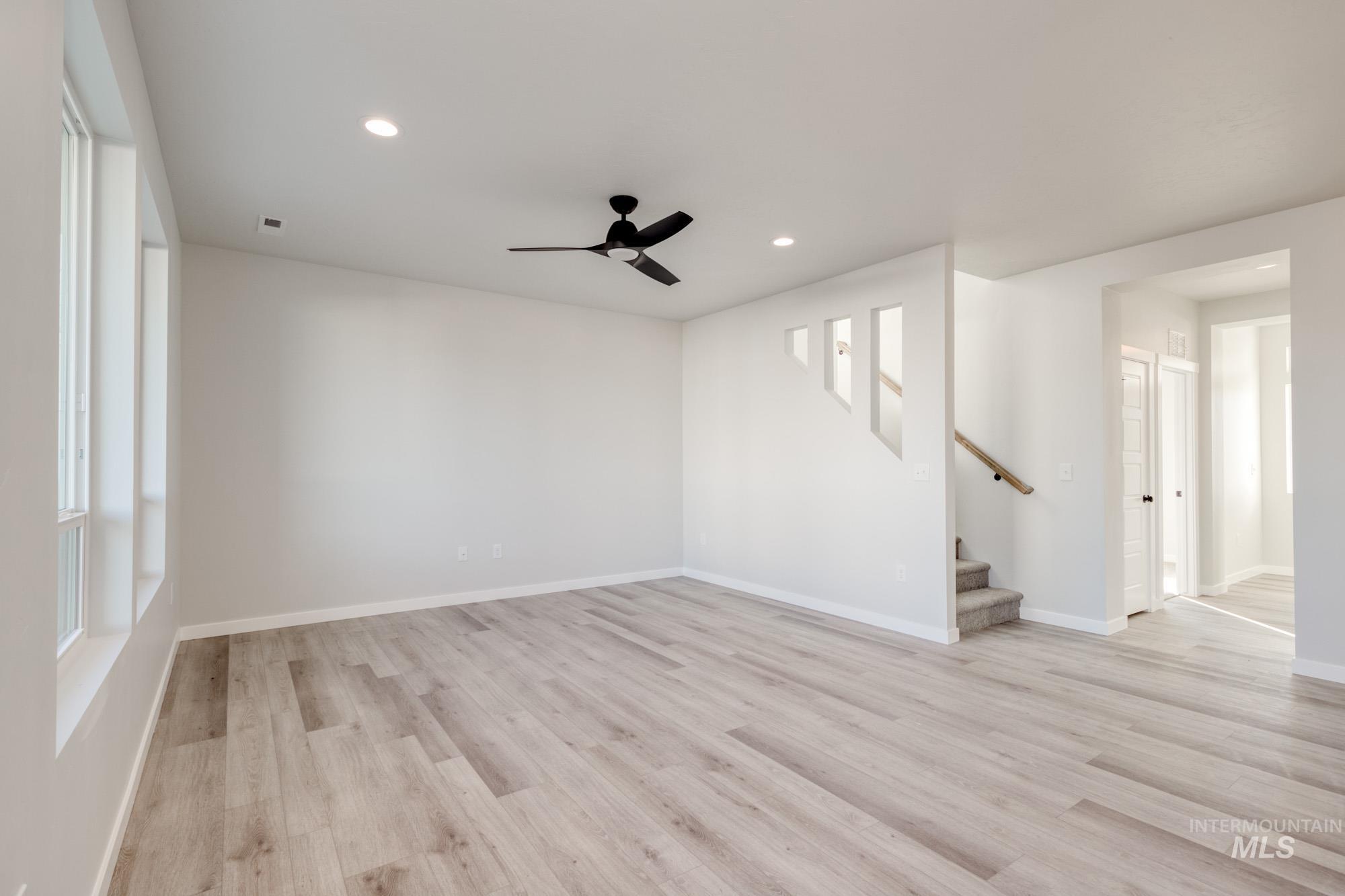 Unfurnished living room with recessed lighting, a ceiling fan, light wood-style floors, and stairway