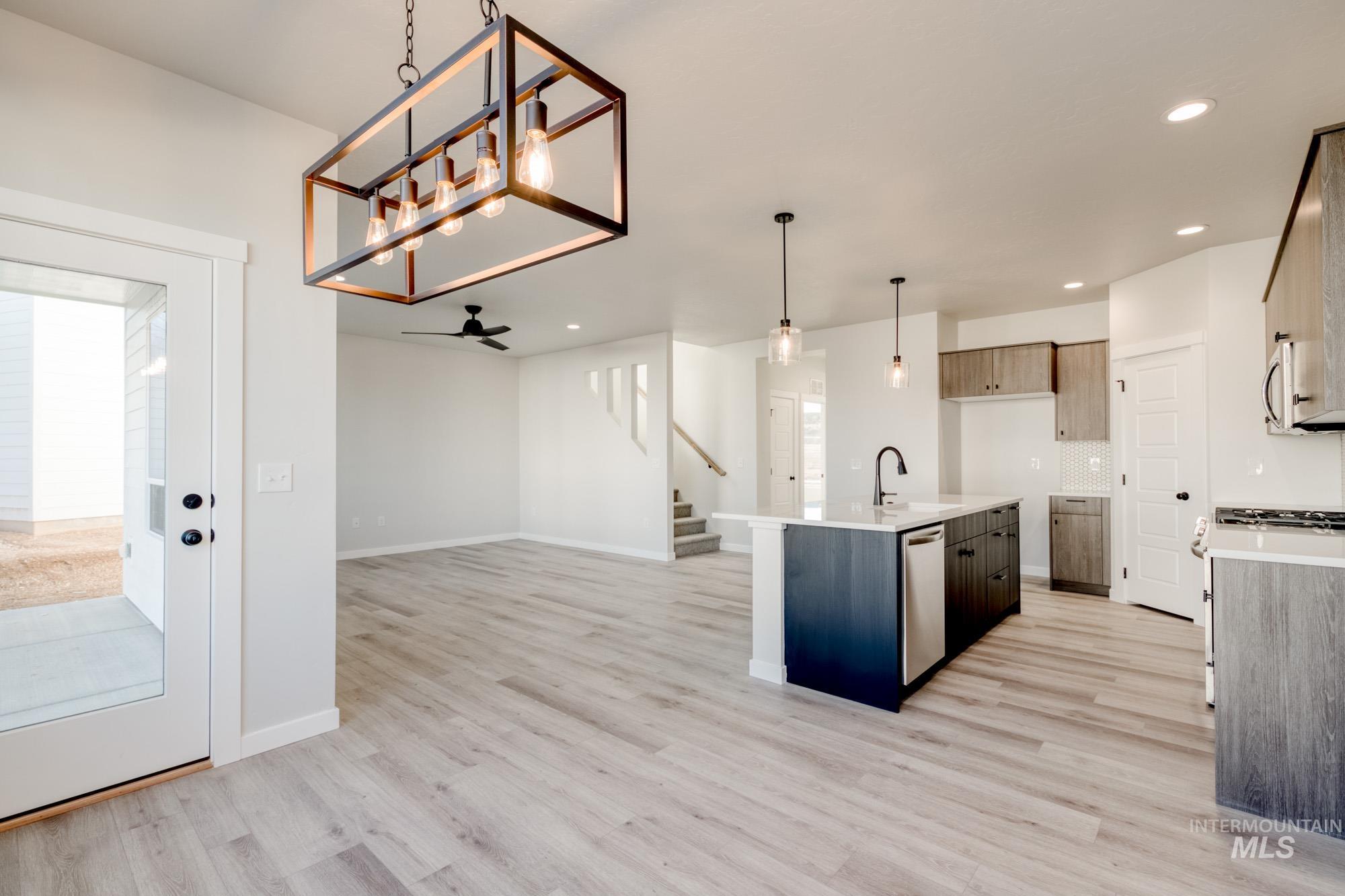Kitchen featuring pendant lighting, a kitchen island with sink, open floor plan, light wood-type flooring, and ceiling fan