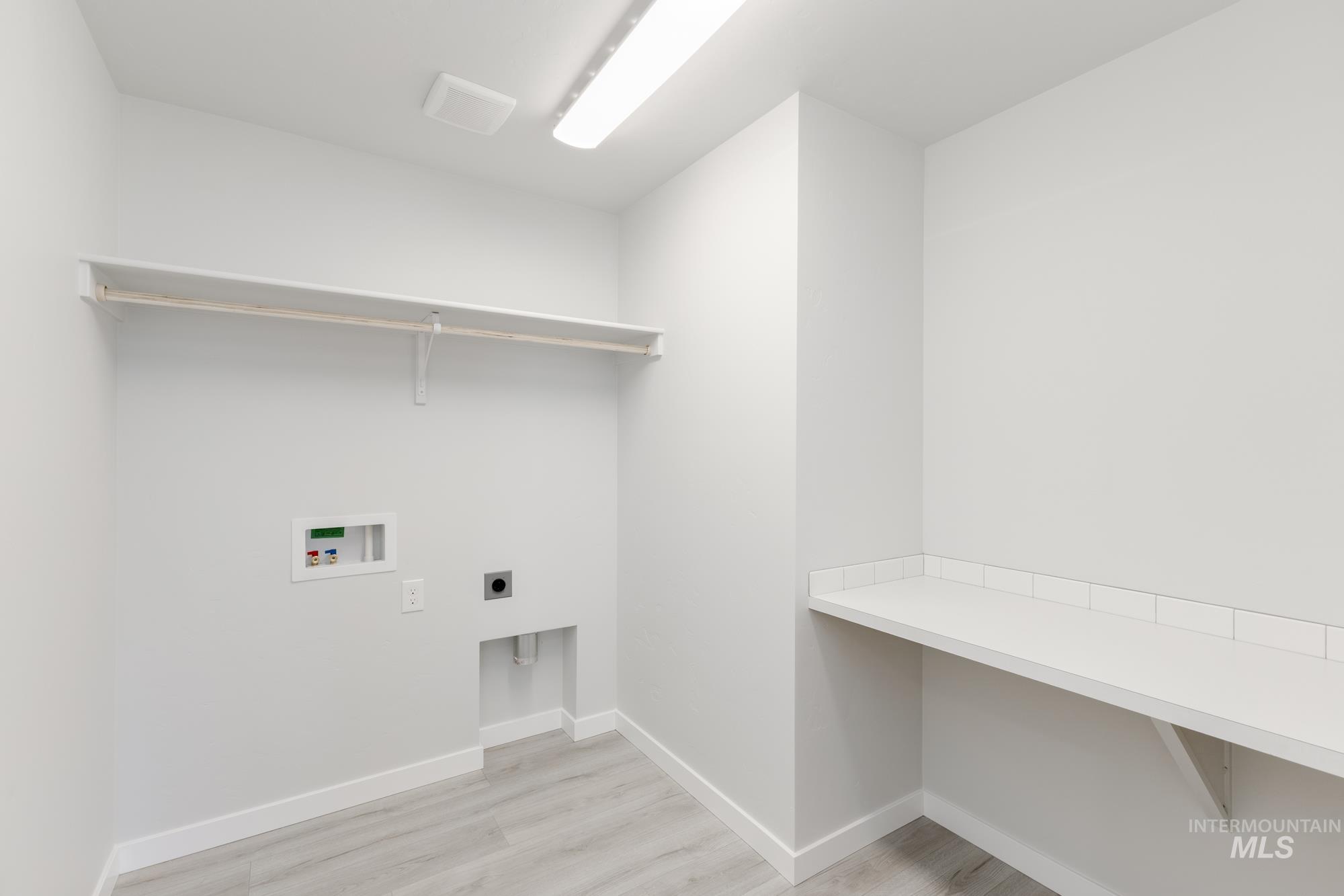 Washroom with hookup for an electric dryer, light wood-style floors, and washer hookup