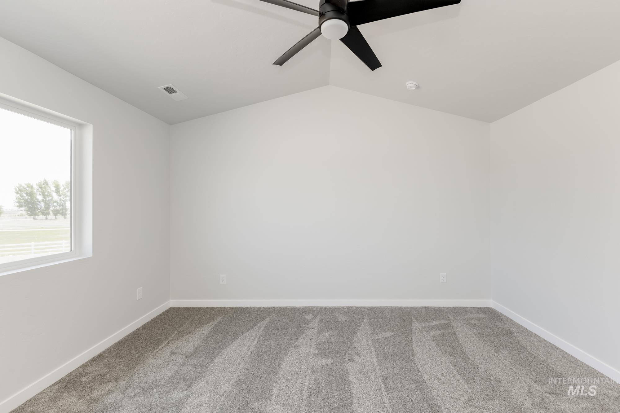 Unfurnished room with carpet floors, ceiling fan, and vaulted ceiling
