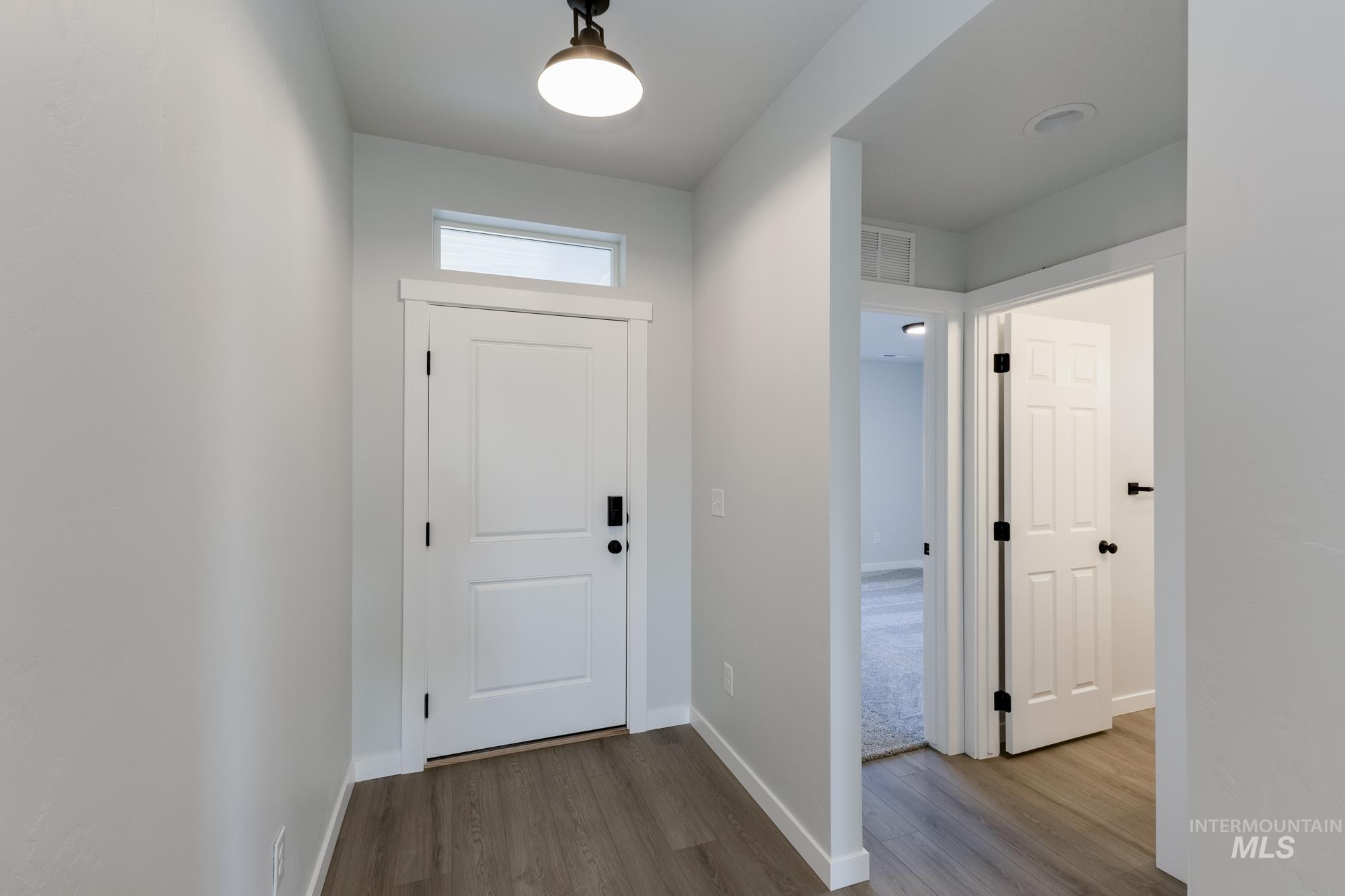 Doorway with baseboards and wood finished floors