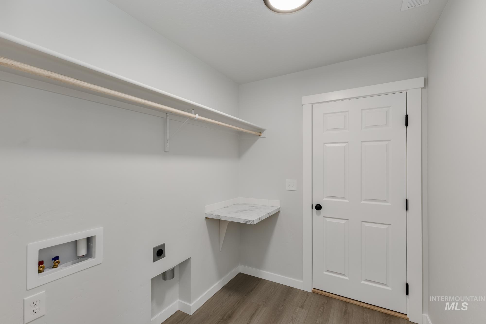 Washroom with light wood finished floors, hookup for a washing machine, and electric dryer hookup