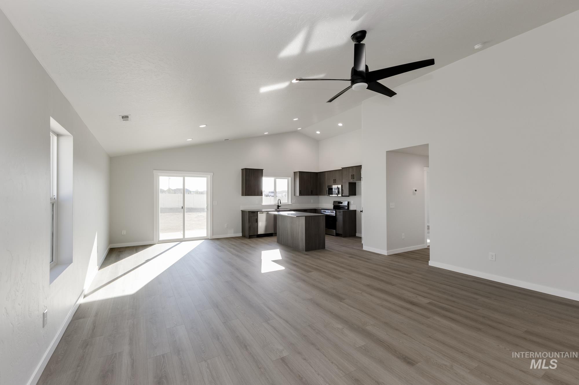 Unfurnished living room featuring light wood finished floors, high vaulted ceiling, a ceiling fan, and recessed lighting