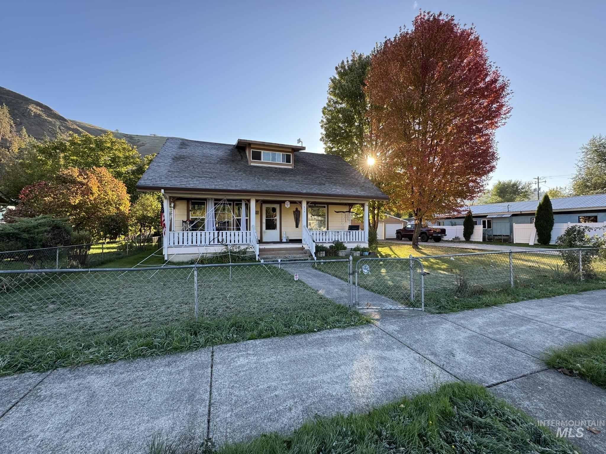 Bungalow-style house with a porch, a shingled roof, and a fenced front yard
