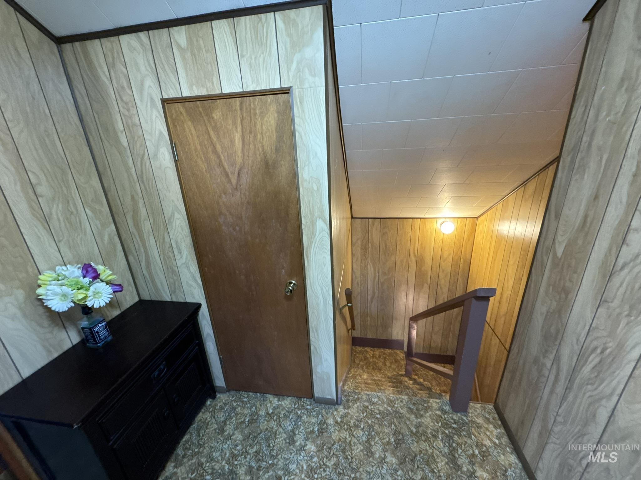 Corridor featuring an upstairs landing and wooden walls