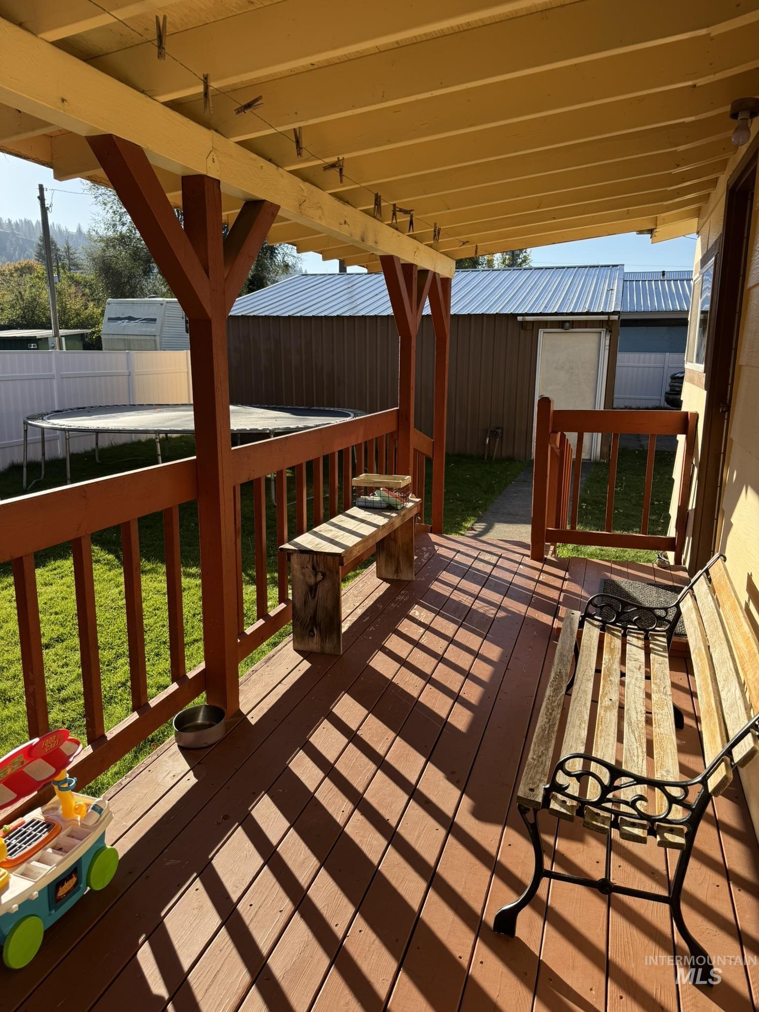 Deck featuring a fenced backyard, a trampoline, and an outdoor structure