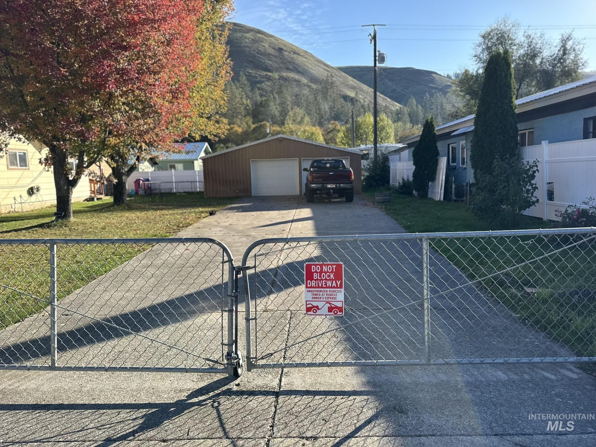 Single story home with a garage, a mountain view, an outbuilding, and a gate