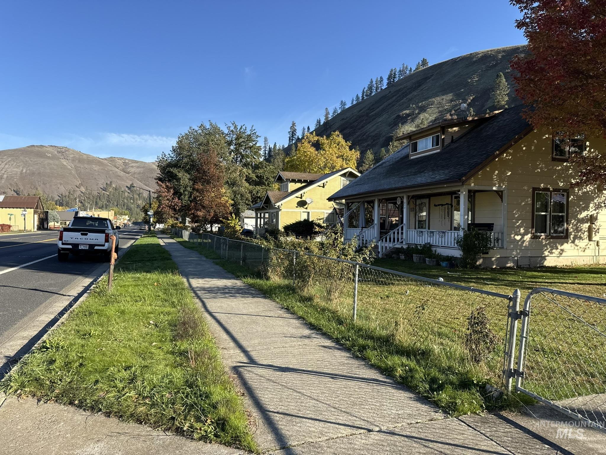 View of asphalt road featuring a mountain view, sidewalks, street lights, and curbs