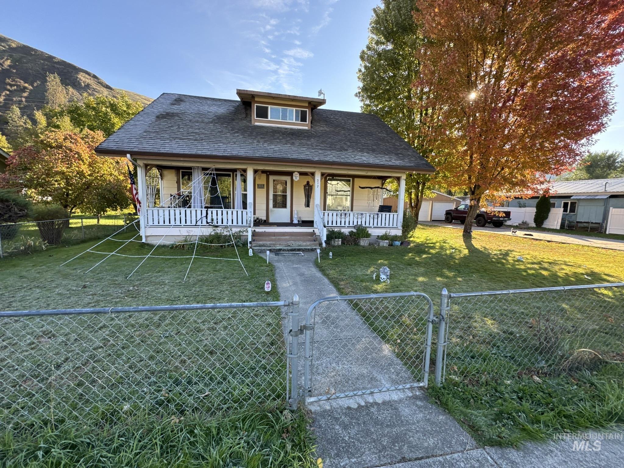 Bungalow with a gate, a shingled roof, covered porch, and a fenced front yard