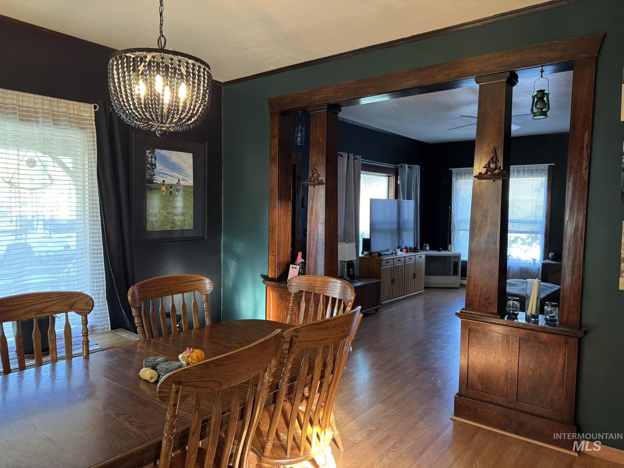 Dining space featuring wood finished floors, a chandelier, and crown molding