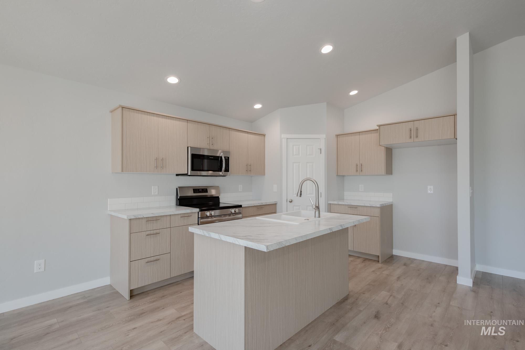Kitchen with light countertops, light brown cabinetry, stainless steel appliances, recessed lighting, and light wood-style floors