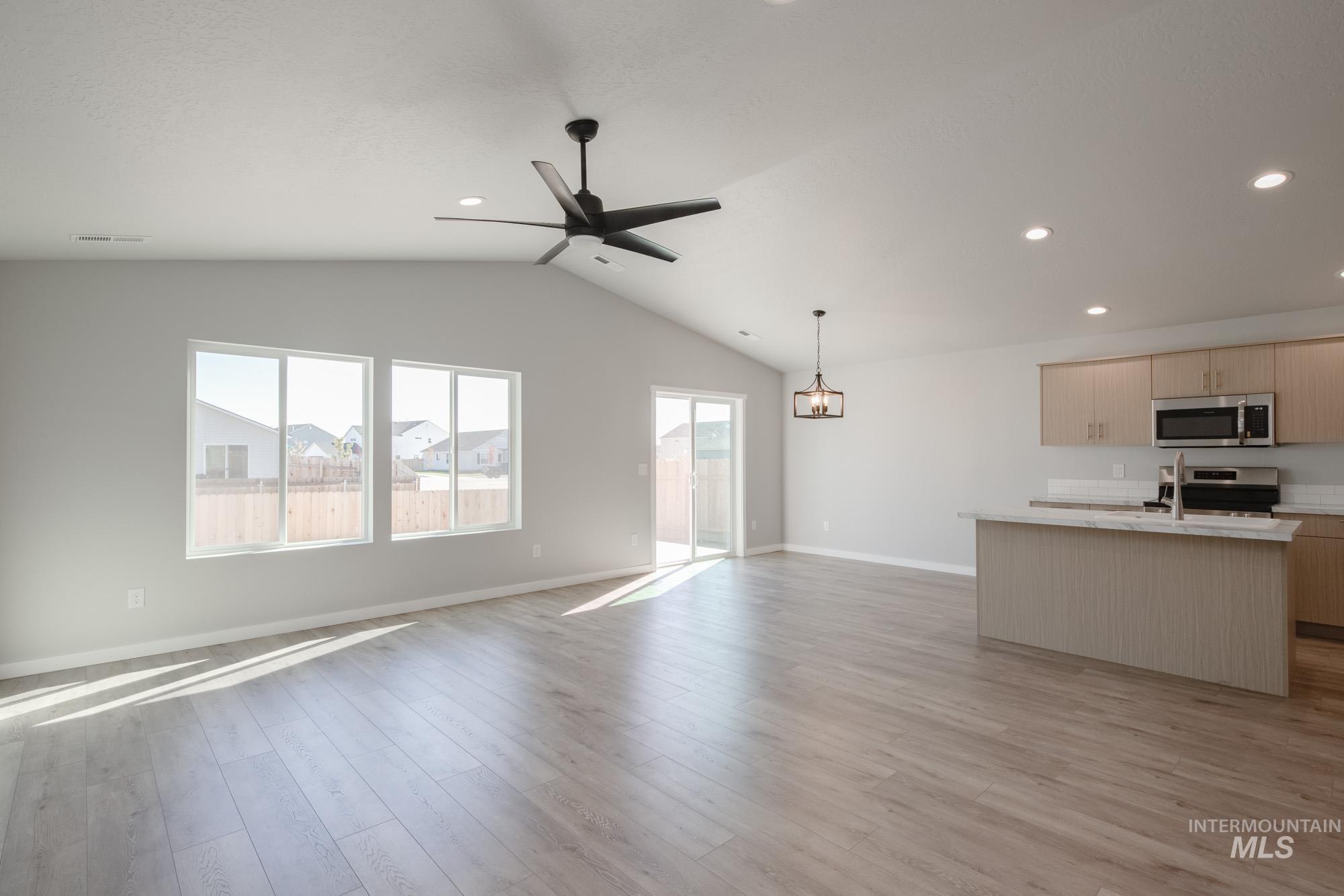 Unfurnished living room with vaulted ceiling, light wood finished floors, recessed lighting, and a ceiling fan