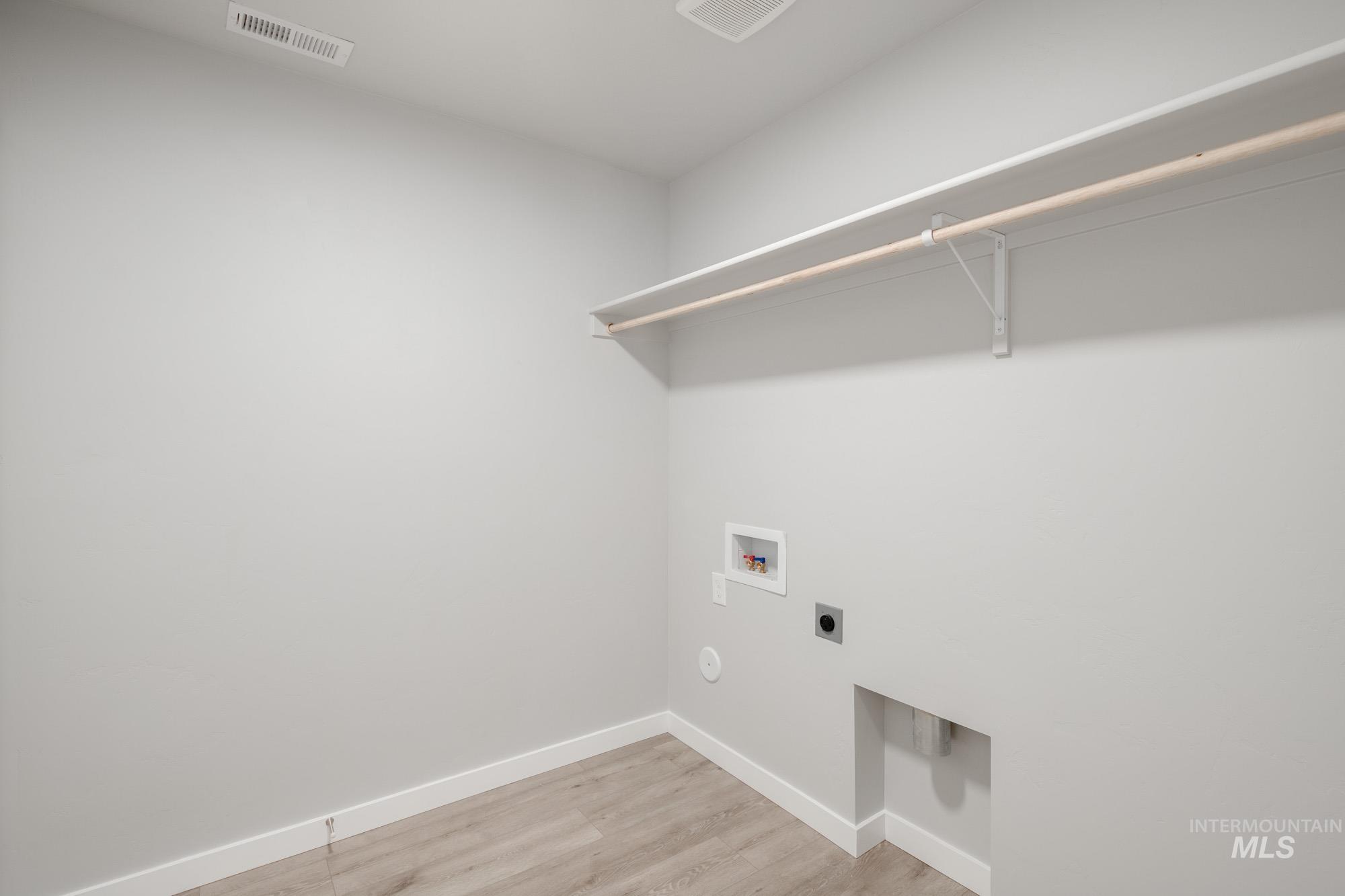 Laundry area featuring light wood finished floors, hookup for a washing machine, and hookup for an electric dryer