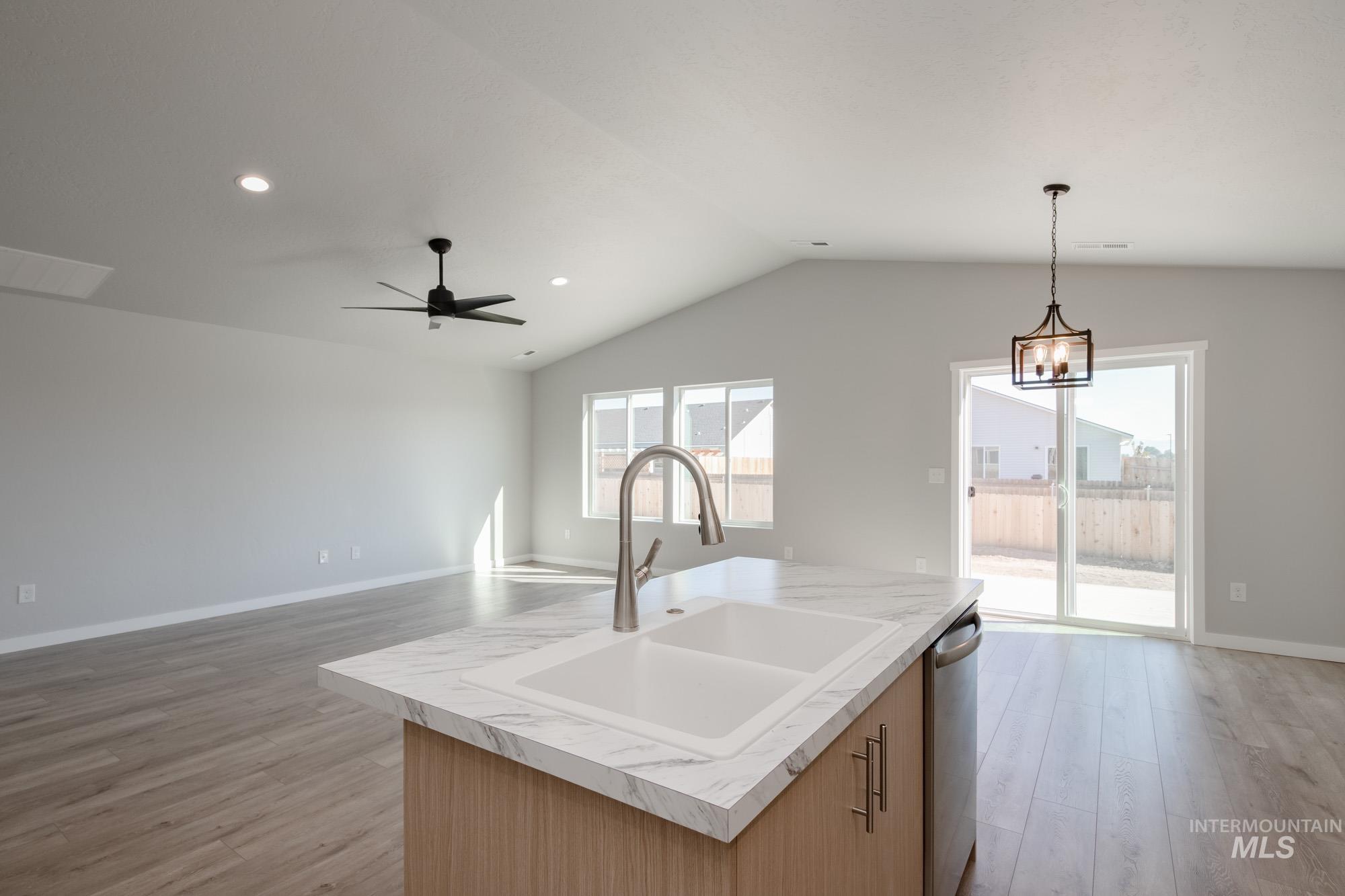 Kitchen featuring light countertops, recessed lighting, open floor plan, light wood-type flooring, and a center island with sink