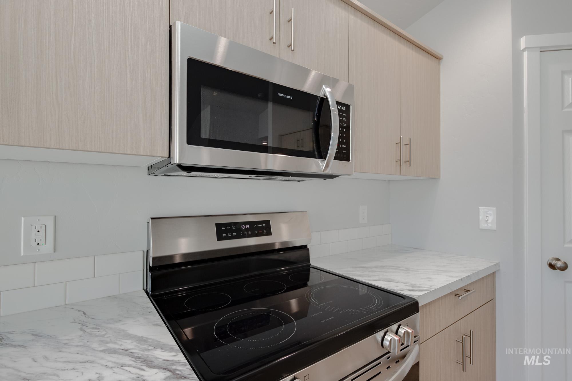 Kitchen featuring stainless steel appliances, light brown cabinetry, light countertops, and modern cabinets