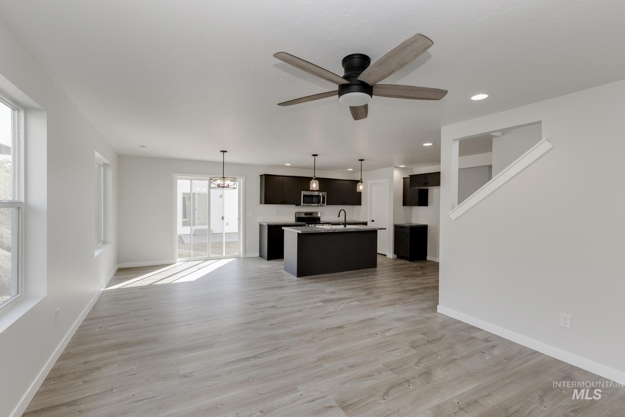Unfurnished living room featuring a chandelier, light wood finished floors, recessed lighting, and a ceiling fan