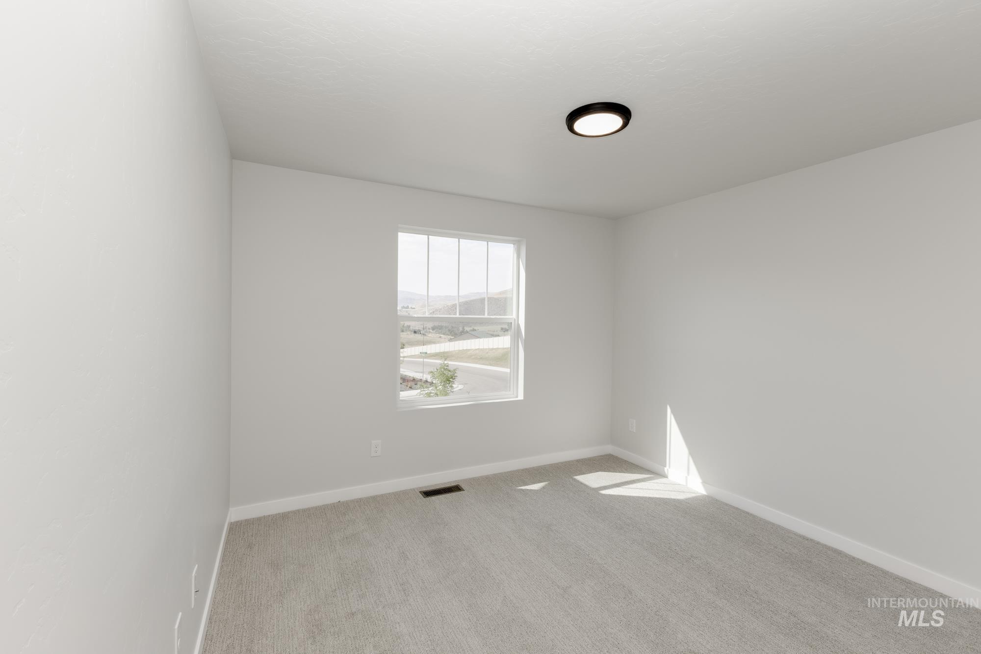 Spare room featuring light carpet and baseboards