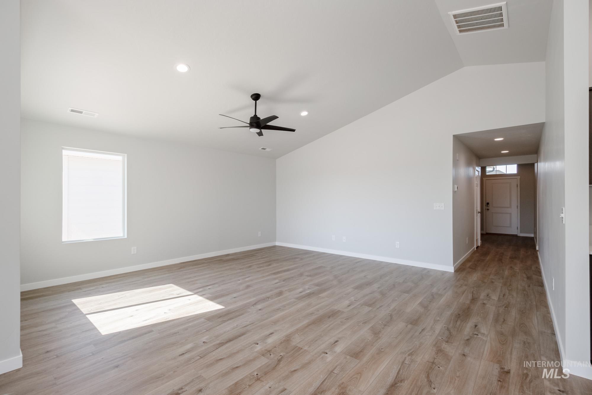 Empty room with vaulted ceiling, light wood finished floors, recessed lighting, and ceiling fan