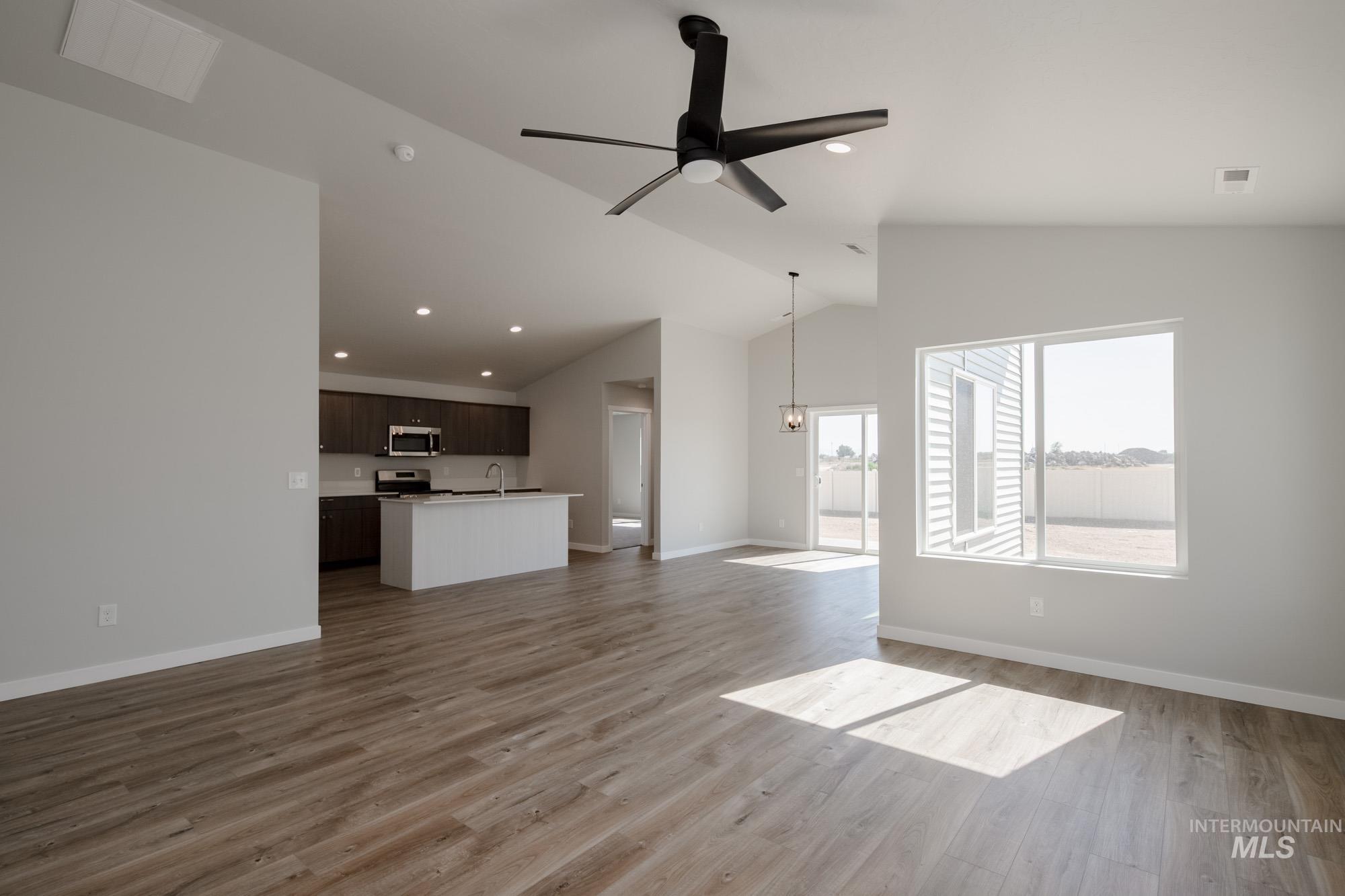 Unfurnished living room with vaulted ceiling, light wood finished floors, ceiling fan, and recessed lighting