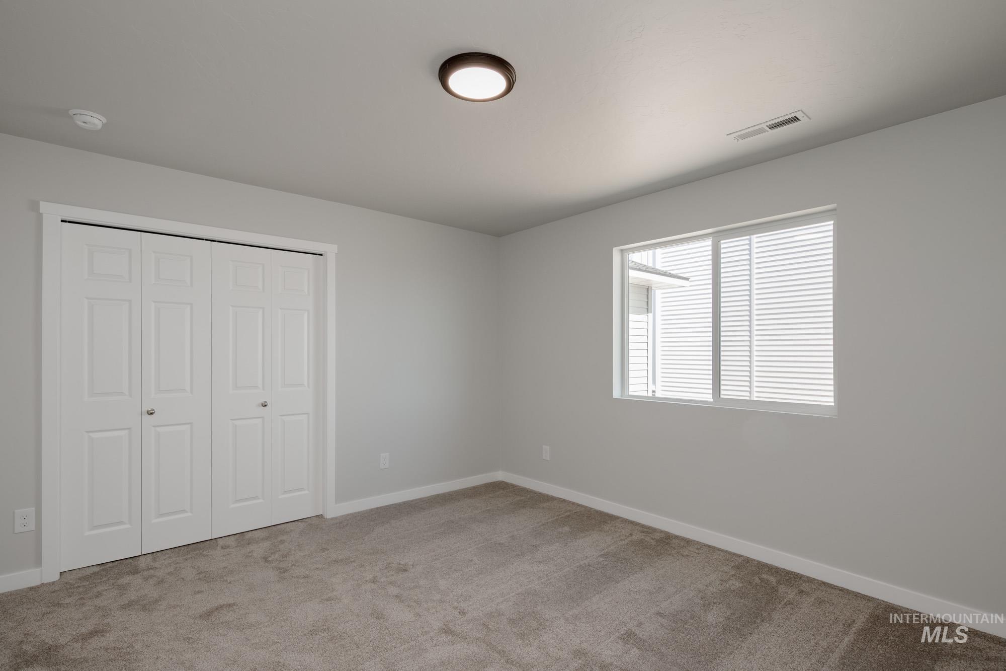 Unfurnished bedroom with light carpet and a closet