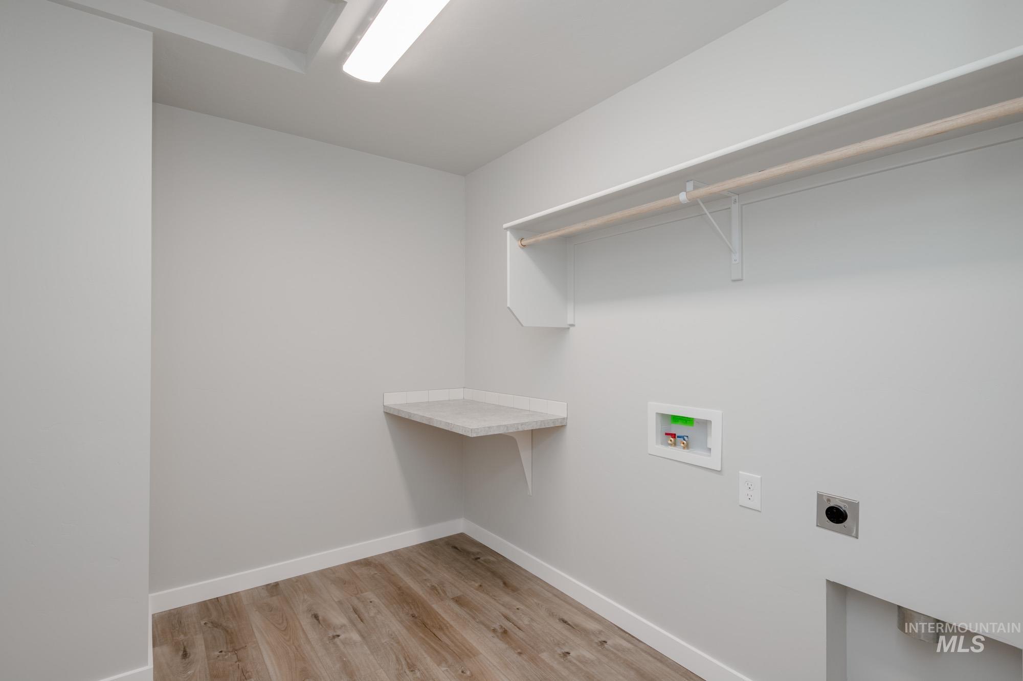 Washroom with light wood-type flooring, electric dryer hookup, and hookup for a washing machine